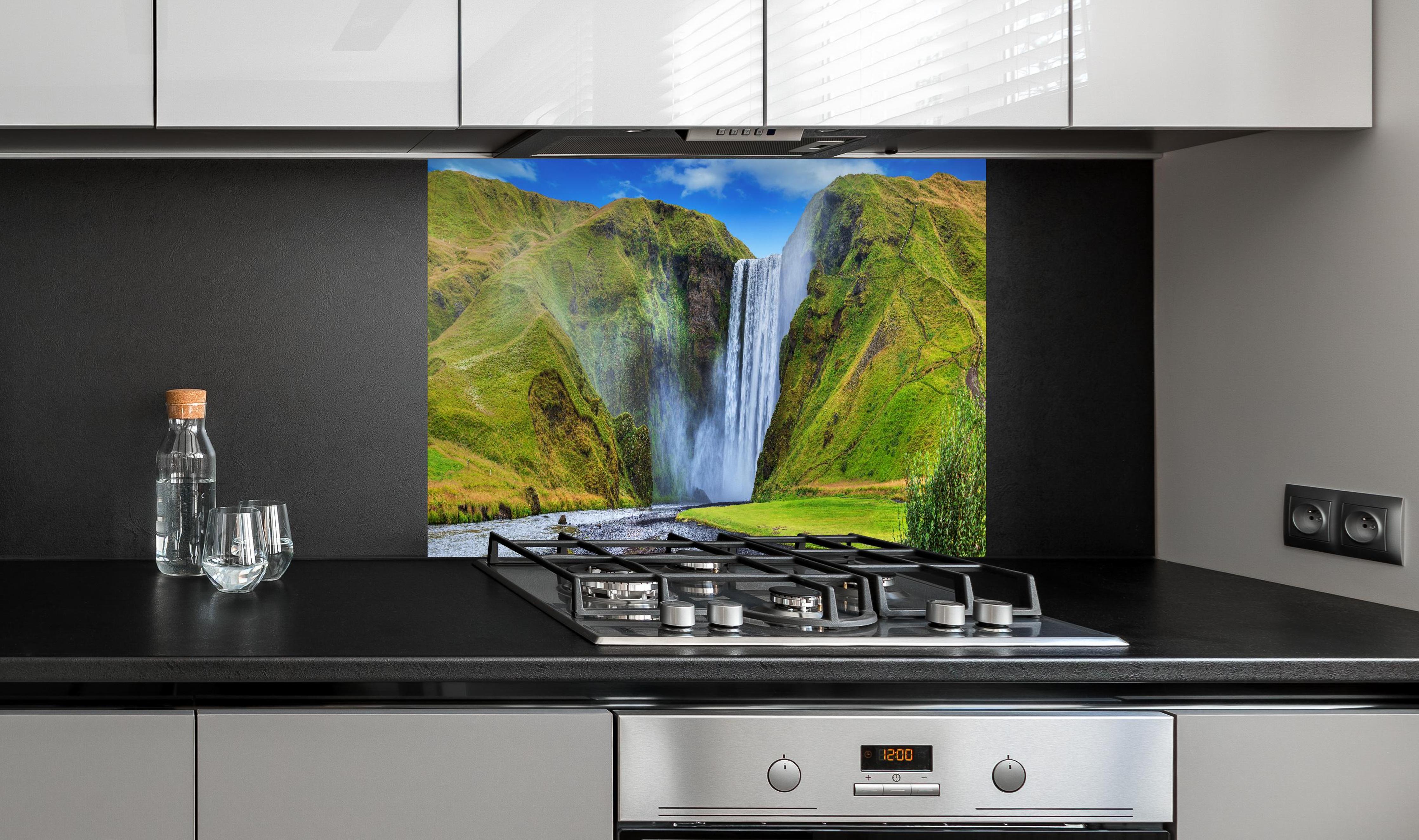 Spritzschutz - Kraftvoller Wasserfall hinter einem Cerankochfeld zwischen Holz-Kochutensilien