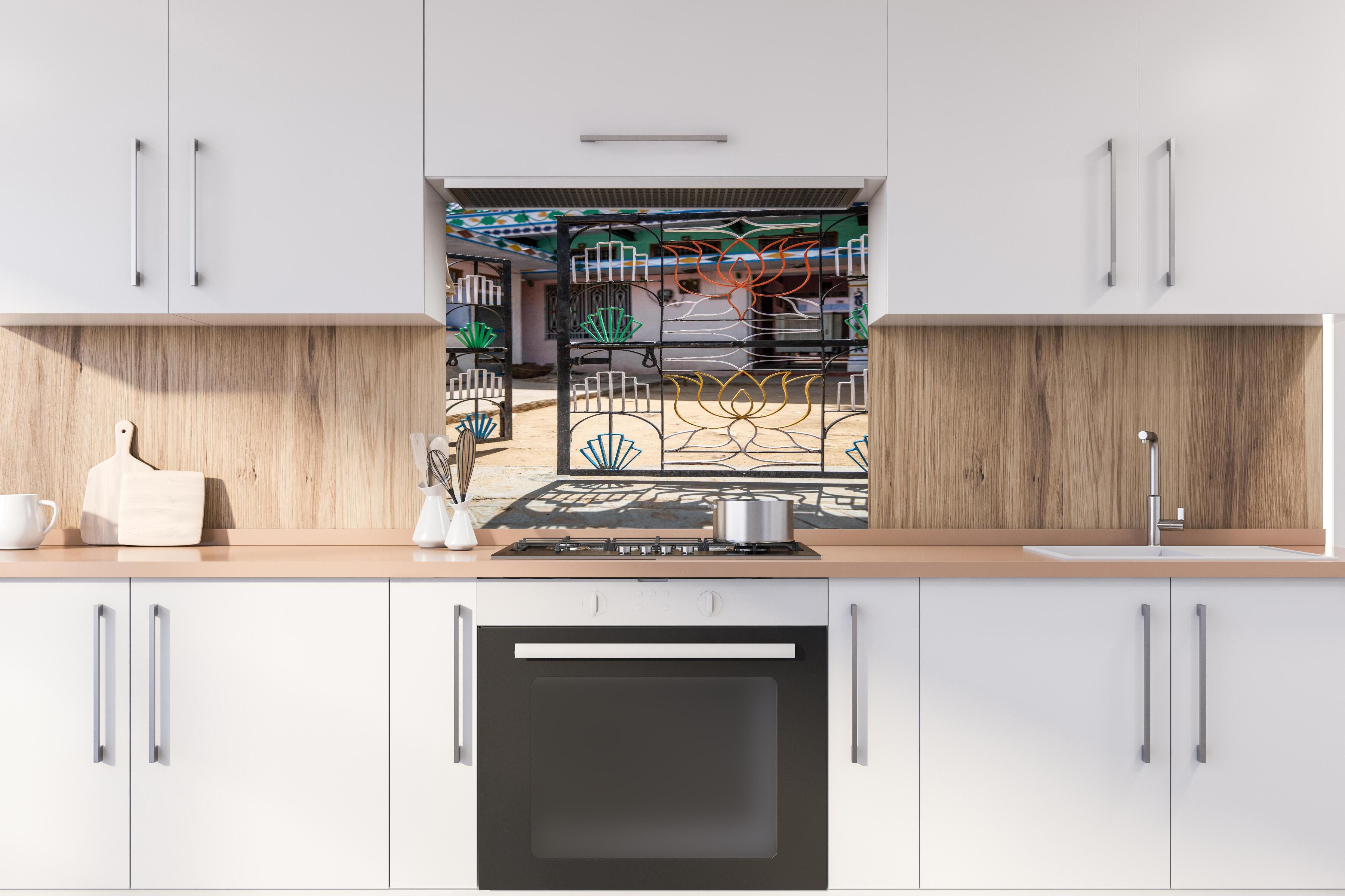 Spritzschutz - Künstlerisches Lotus-Tor gegen Hausfassade hinter einem Cerankochfeld zwischen Holz-Kochutensilien