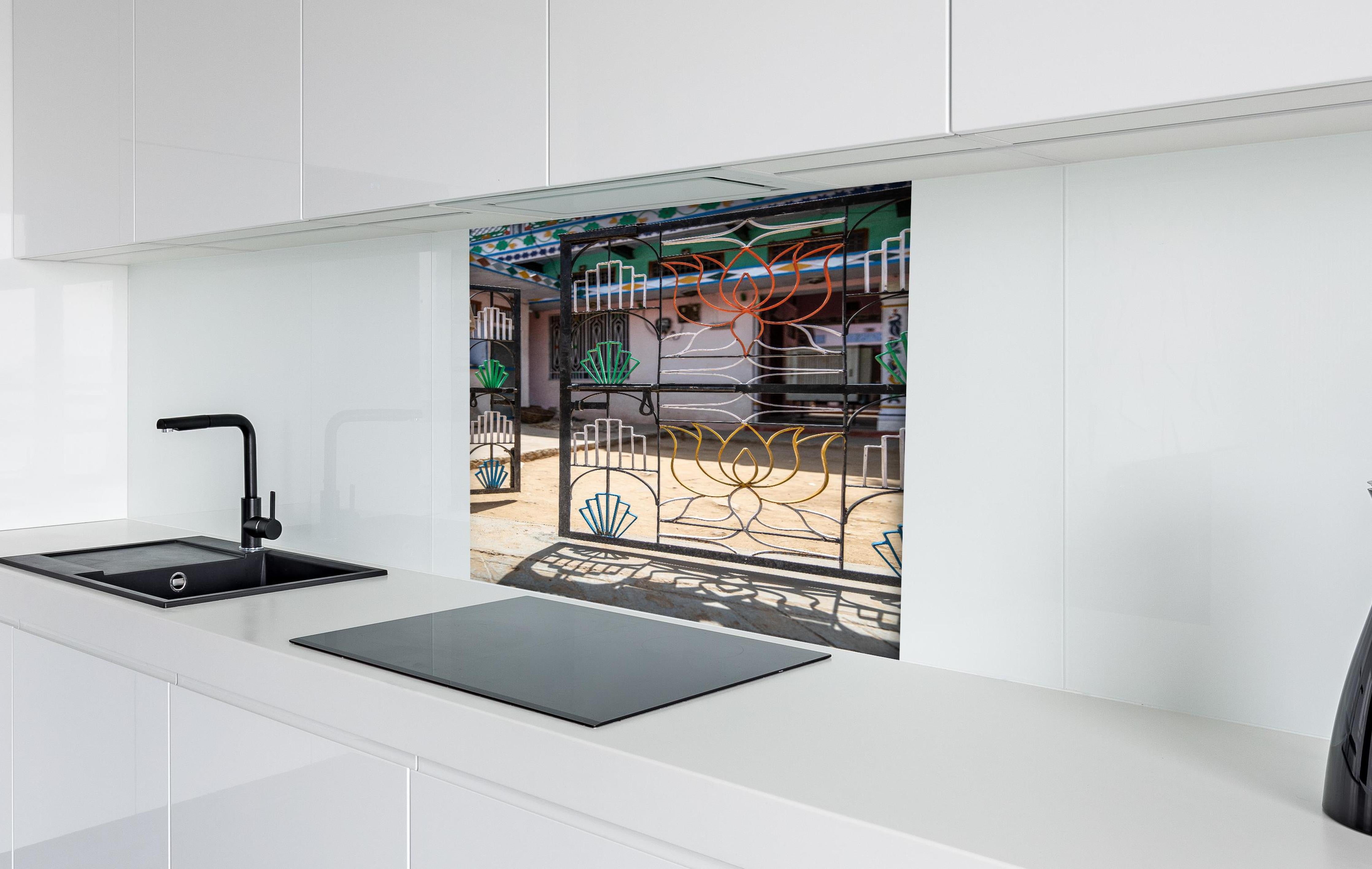 Spritzschutz - Künstlerisches Lotus-Tor gegen Hausfassade hinter einem Cerankochfeld zwischen Holz-Kochutensilien