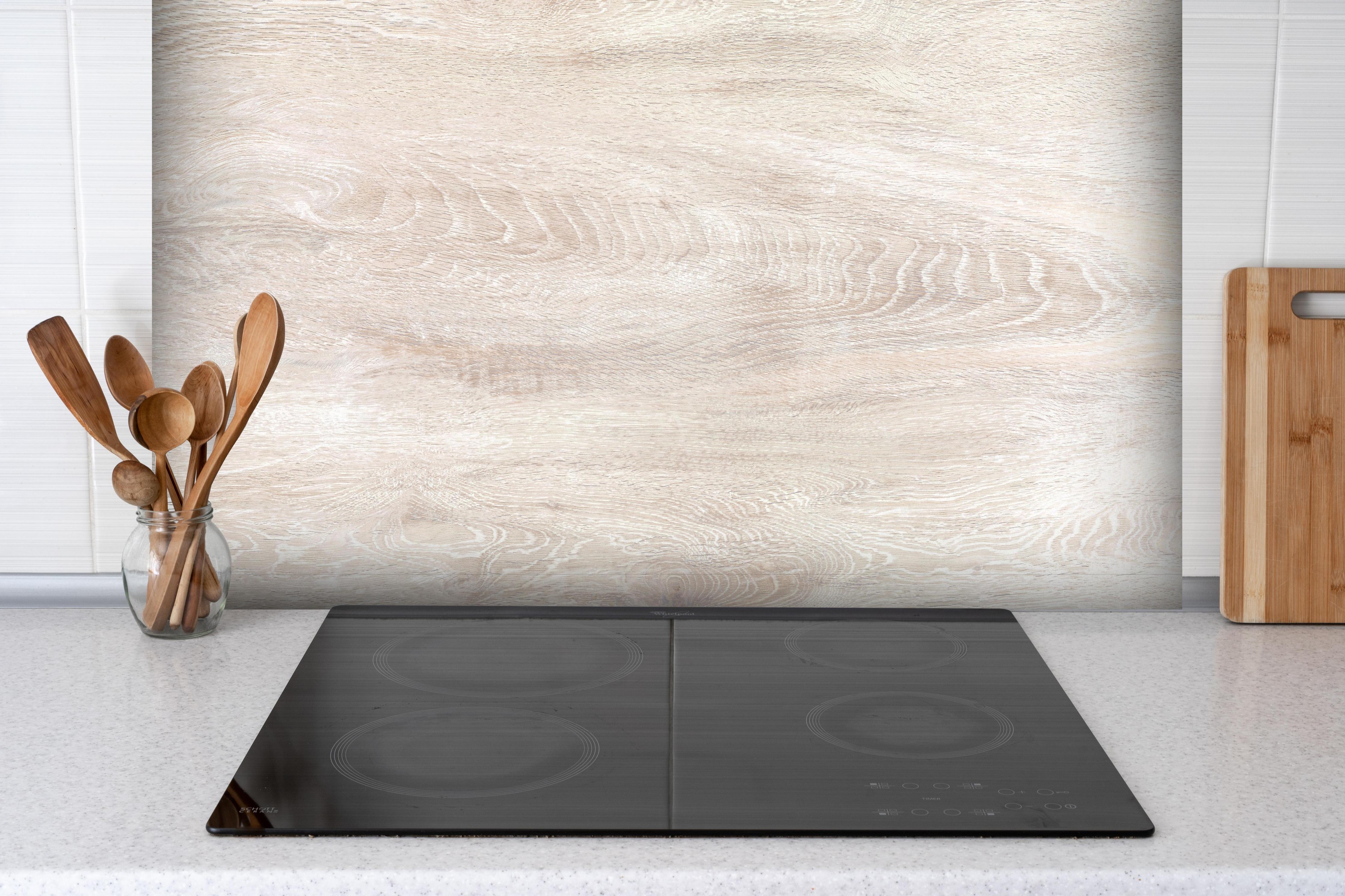 Spritzschutz - Lange beige Holzplatte hinter einem Cerankochfeld zwischen Holz-Kochutensilien