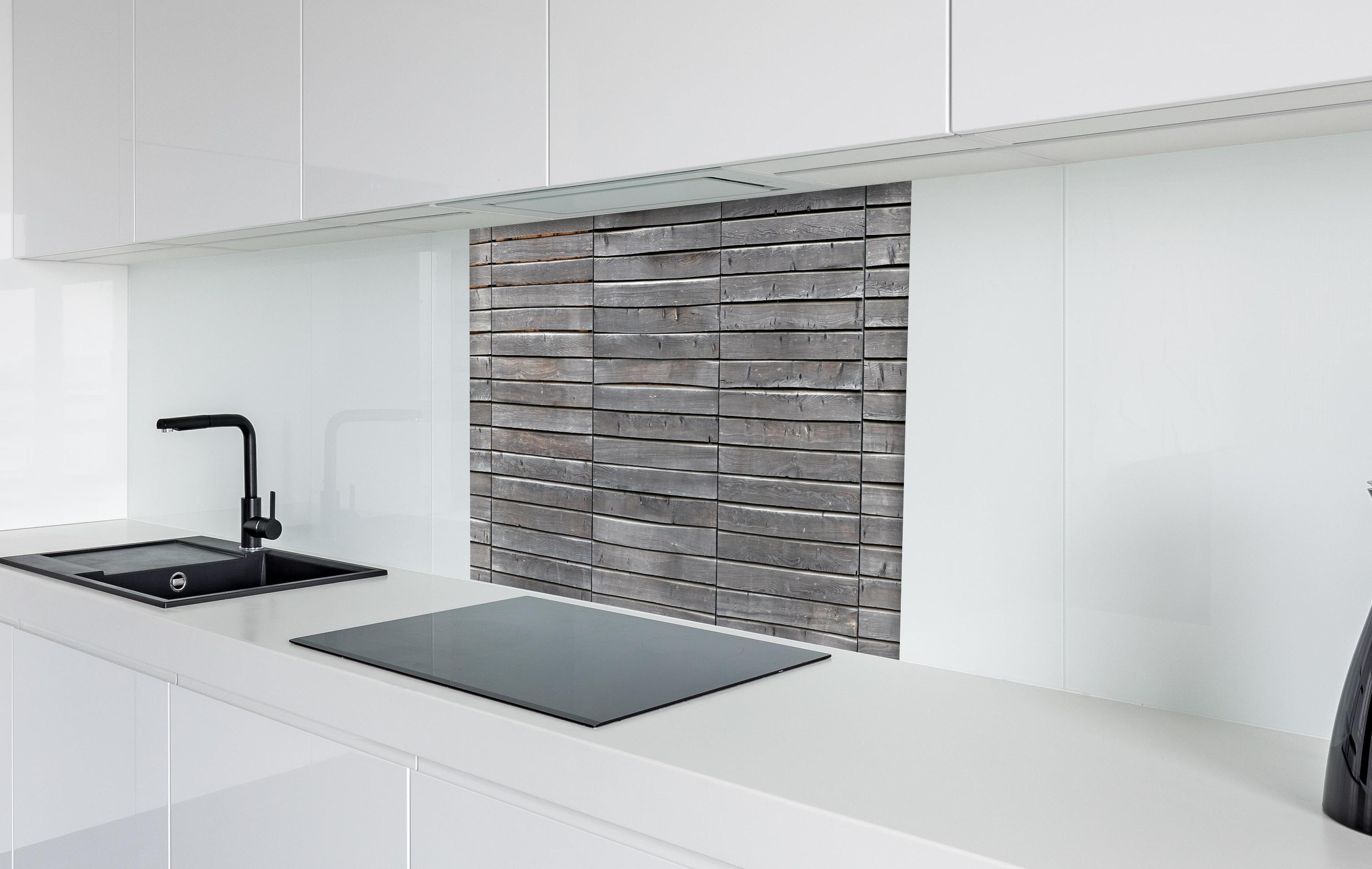 Spritzschutz - Langer grauer Holzzaun hinter einem Cerankochfeld zwischen Holz-Kochutensilien