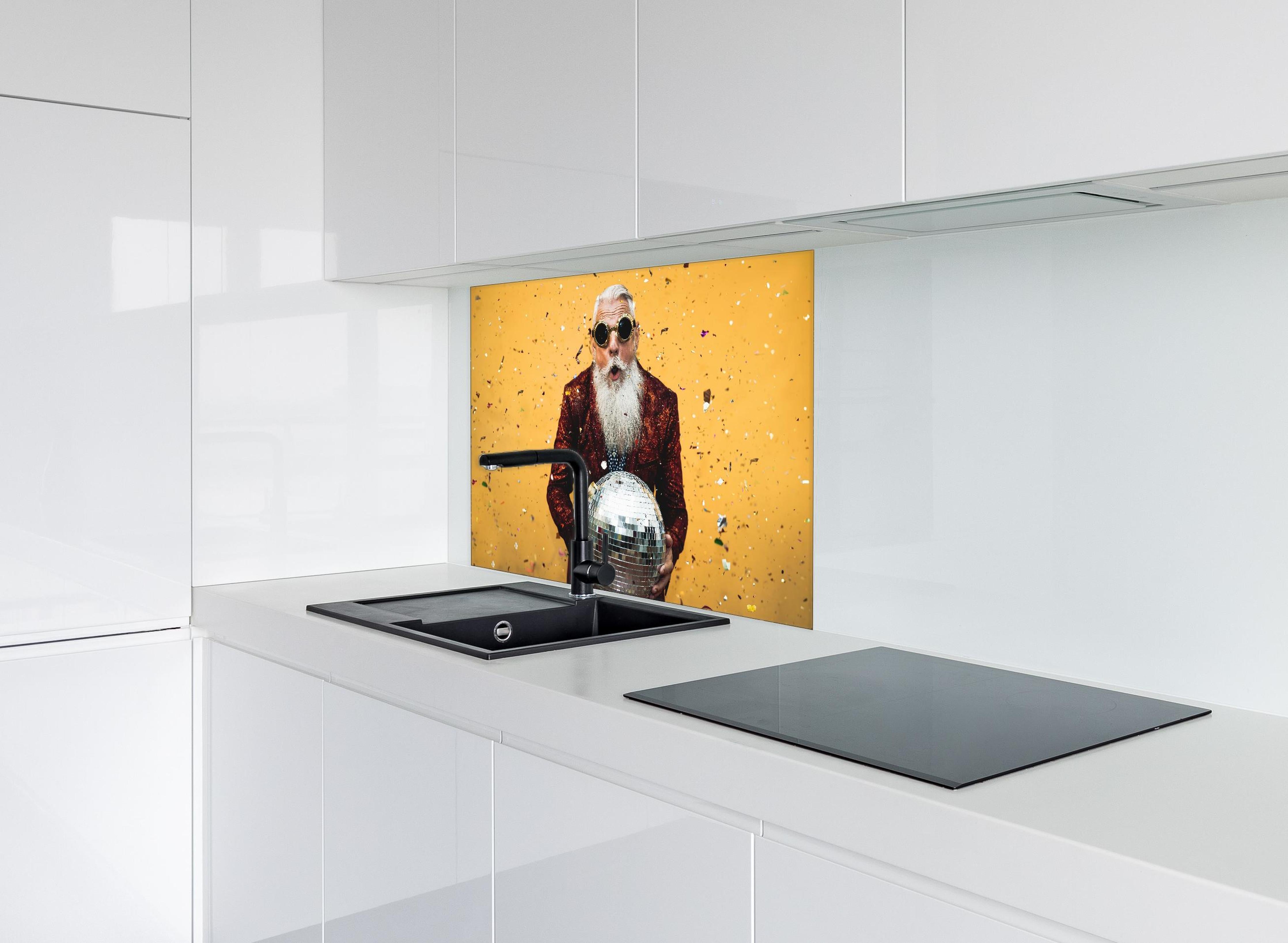 Spritzschutz - Lebensfroher Senior feiert mit Discokugel hinter einem Cerankochfeld zwischen Holz-Kochutensilien