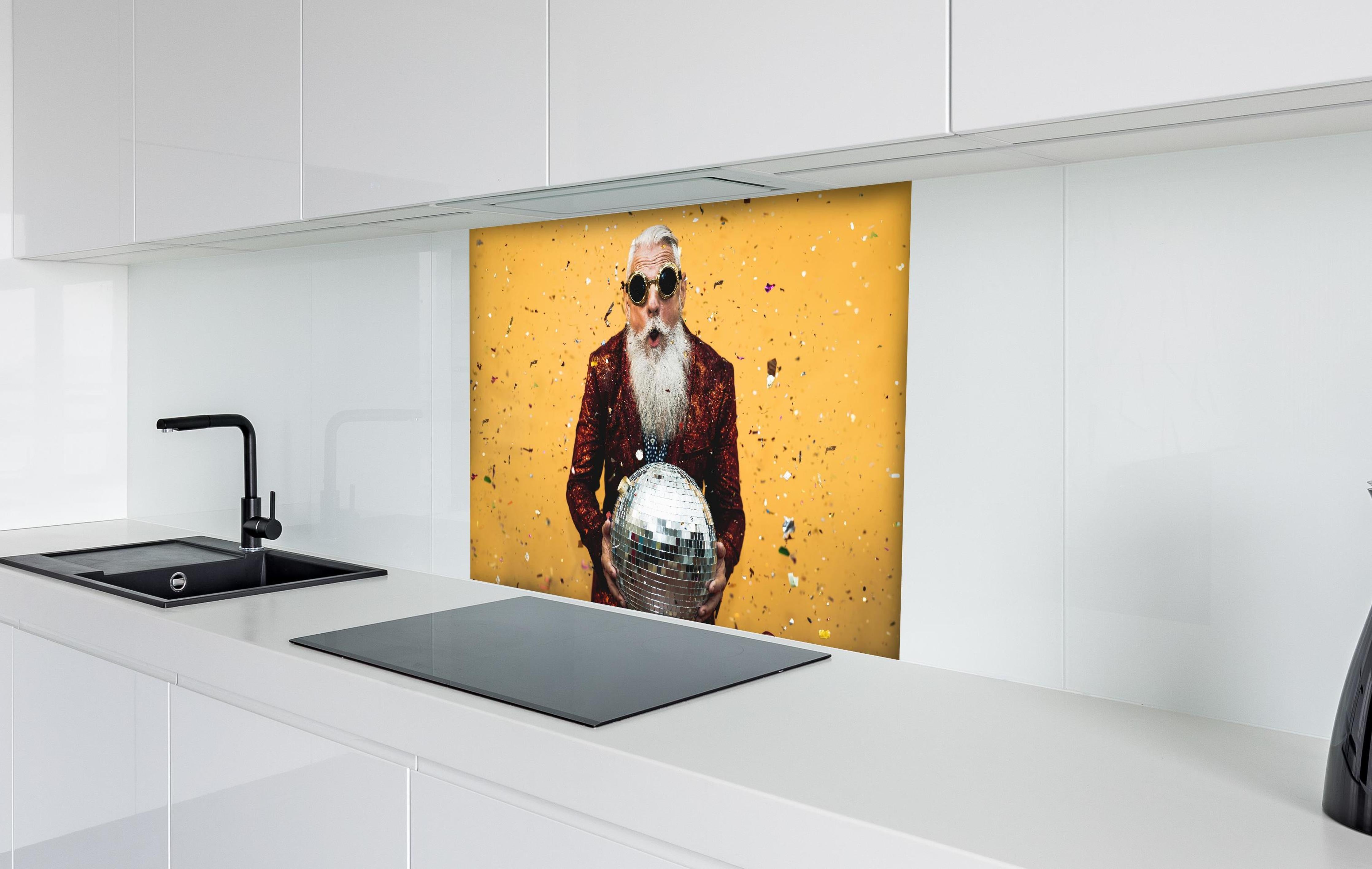 Spritzschutz - Lebensfroher Senior feiert mit Discokugel hinter einem Cerankochfeld zwischen Holz-Kochutensilien