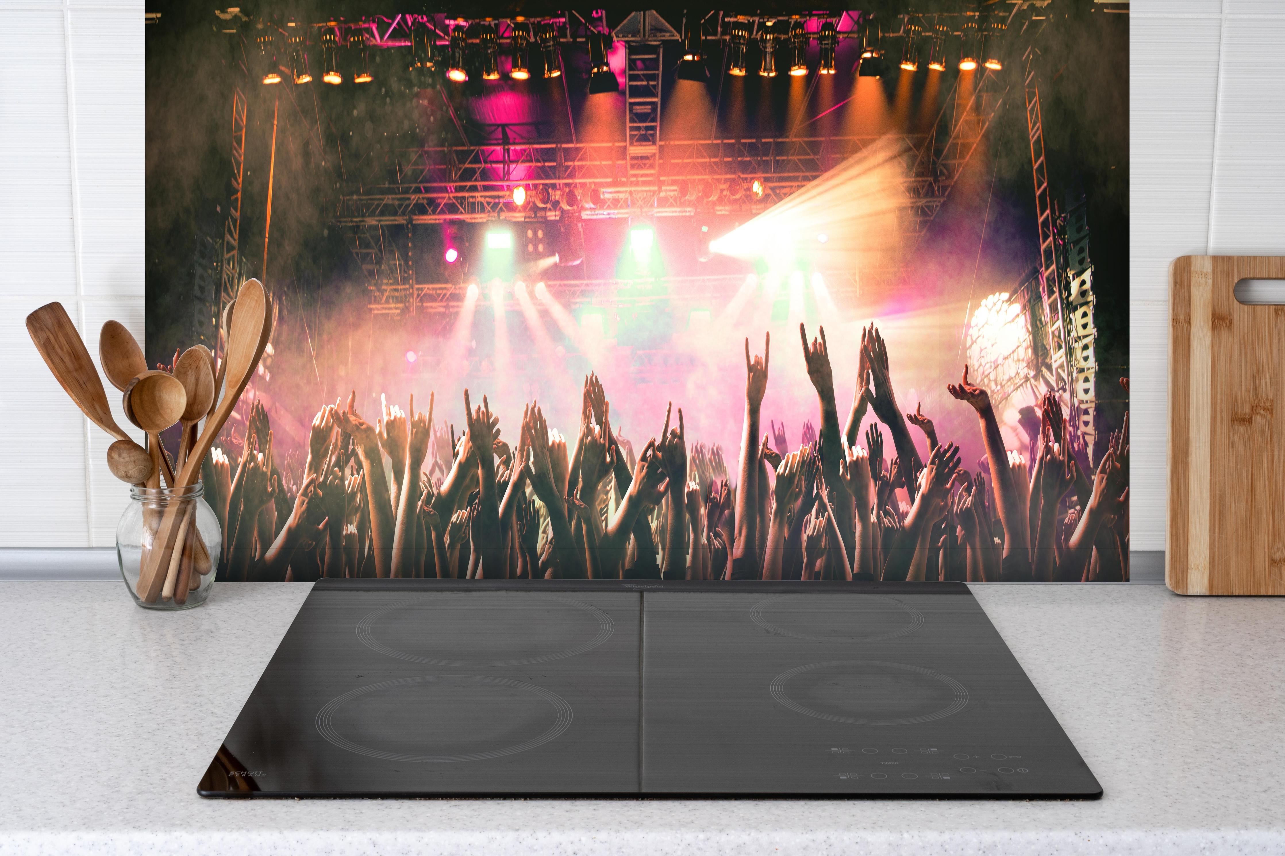 Spritzschutz - Lebhaftes Live-Musikkonzert mit Publikum hinter einem Cerankochfeld zwischen Holz-Kochutensilien