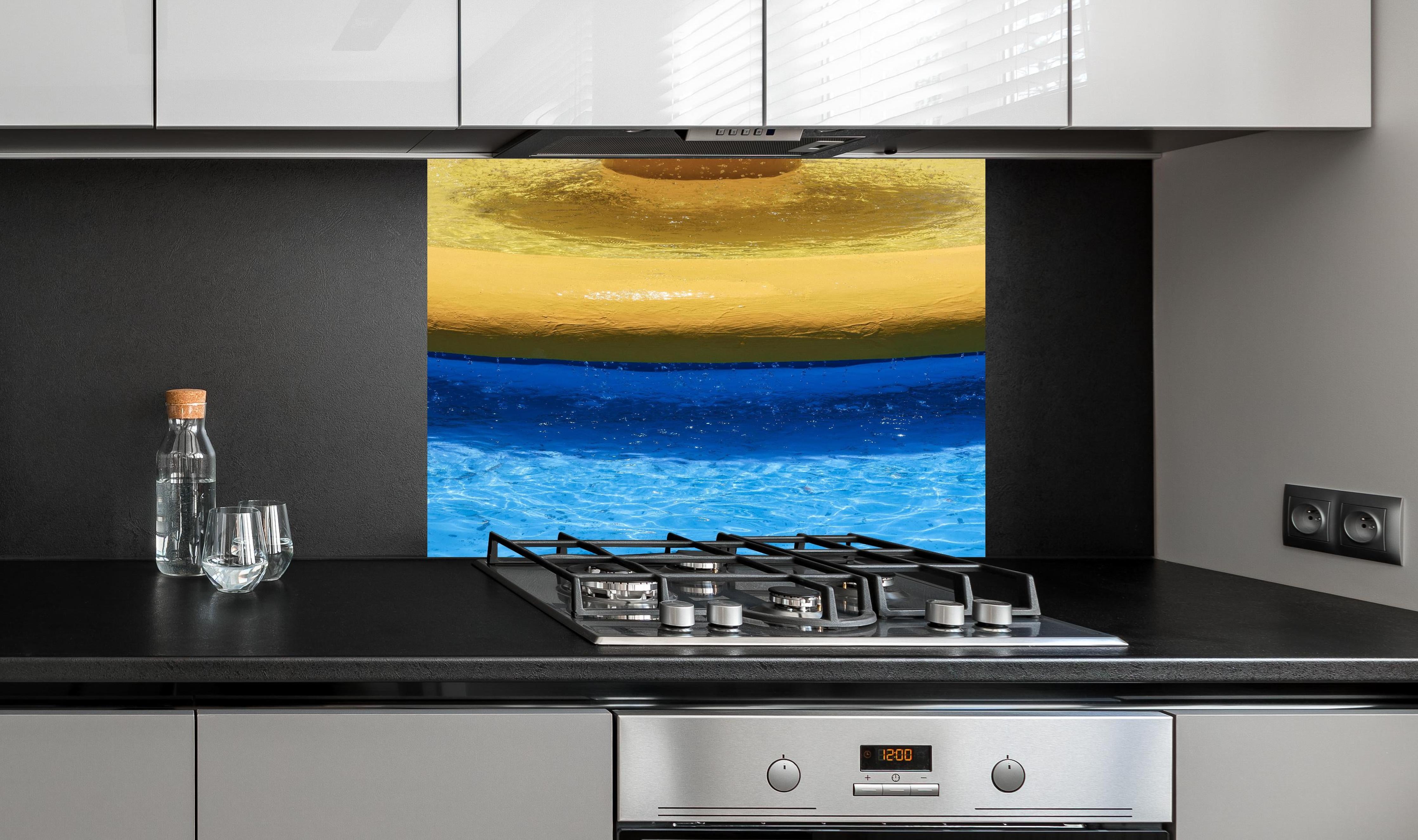 Spritzschutz - Lebhaftes Schwimmbad in Blau und Gelb hinter einem Cerankochfeld zwischen Holz-Kochutensilien