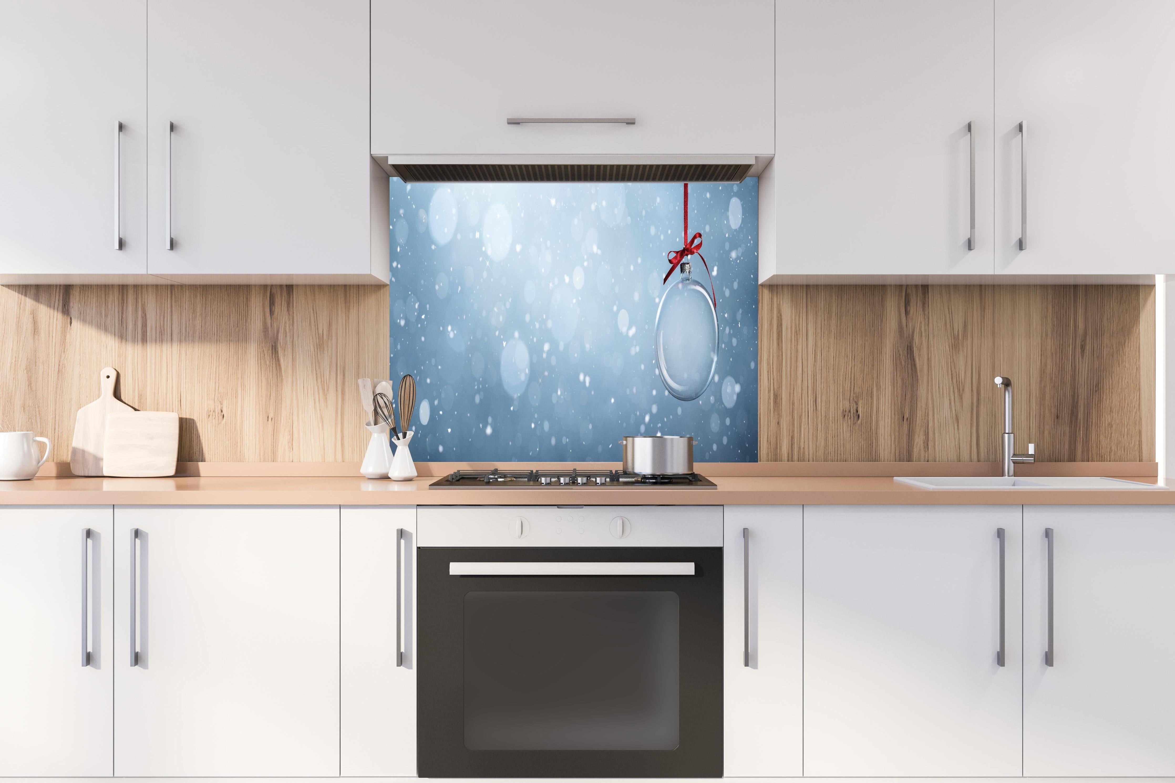 Spritzschutz - Leere Weihnachtskugel hinter einem Cerankochfeld zwischen Holz-Kochutensilien