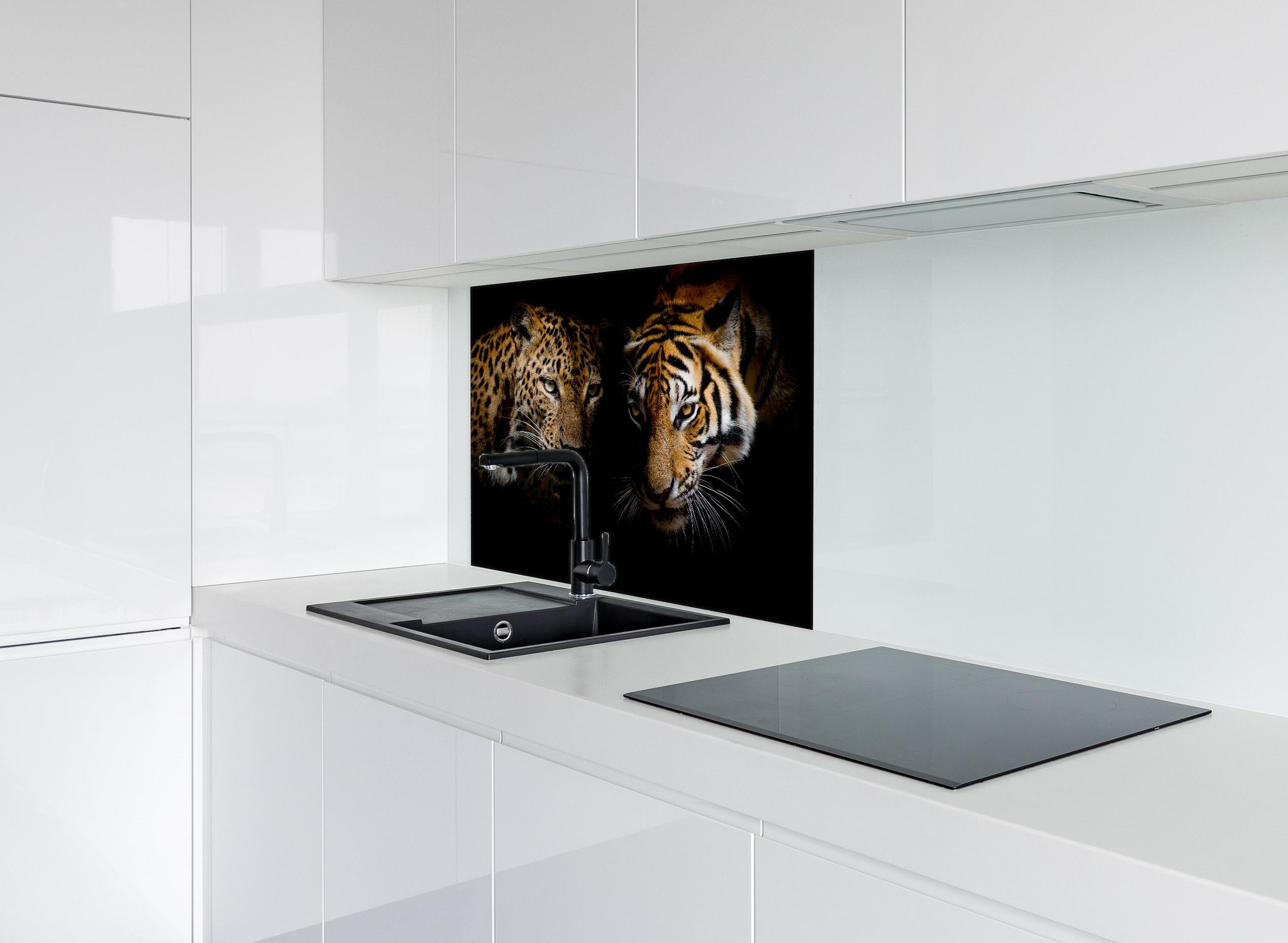 Spritzschutz - Leopard und Tiger isoliert auf schwarzen Hintergrund hinter einem Cerankochfeld zwischen Holz-Kochutensilien