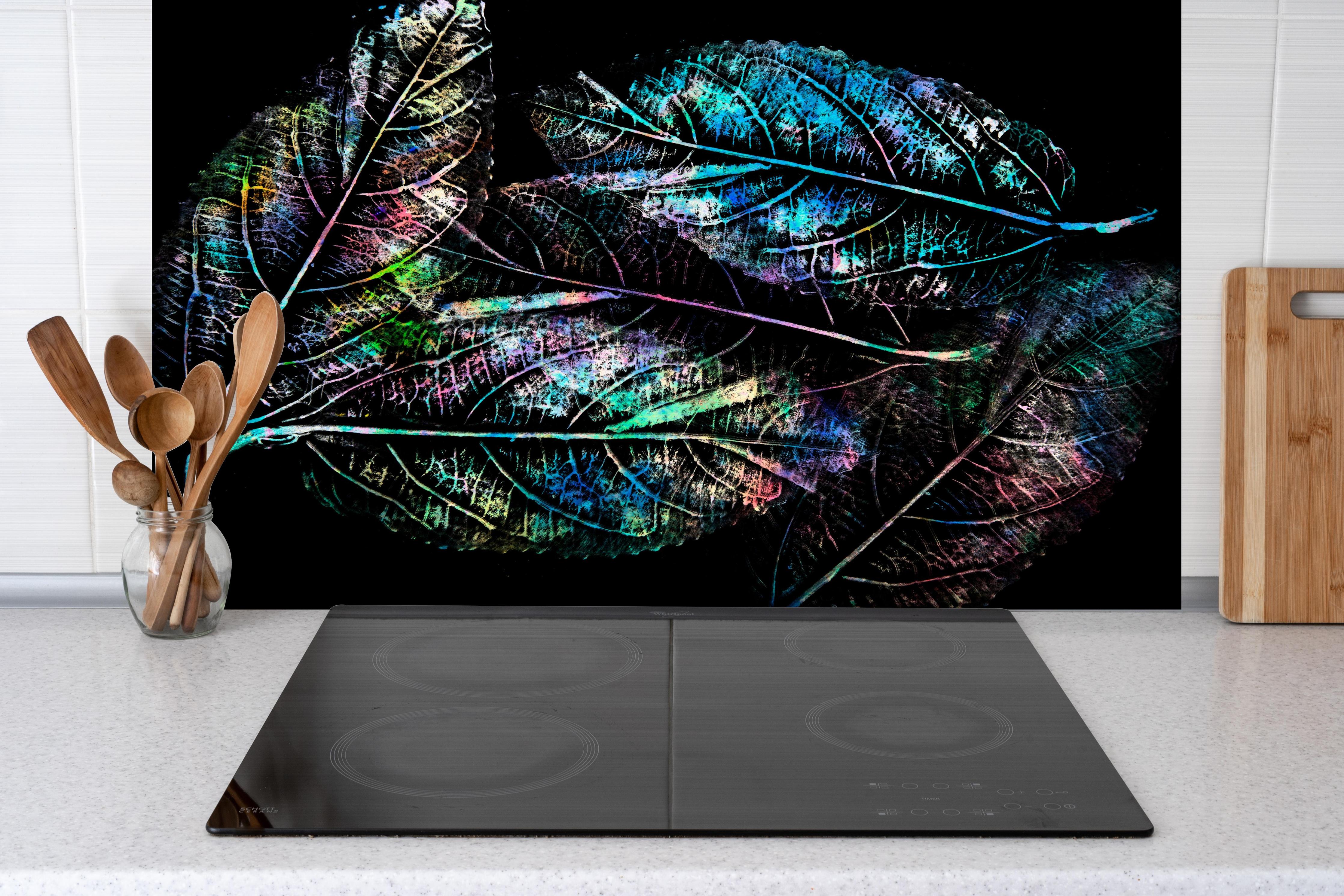 Spritzschutz - Leuchtende Blattadern Bunt auf Schwarz hinter einem Cerankochfeld zwischen Holz-Kochutensilien