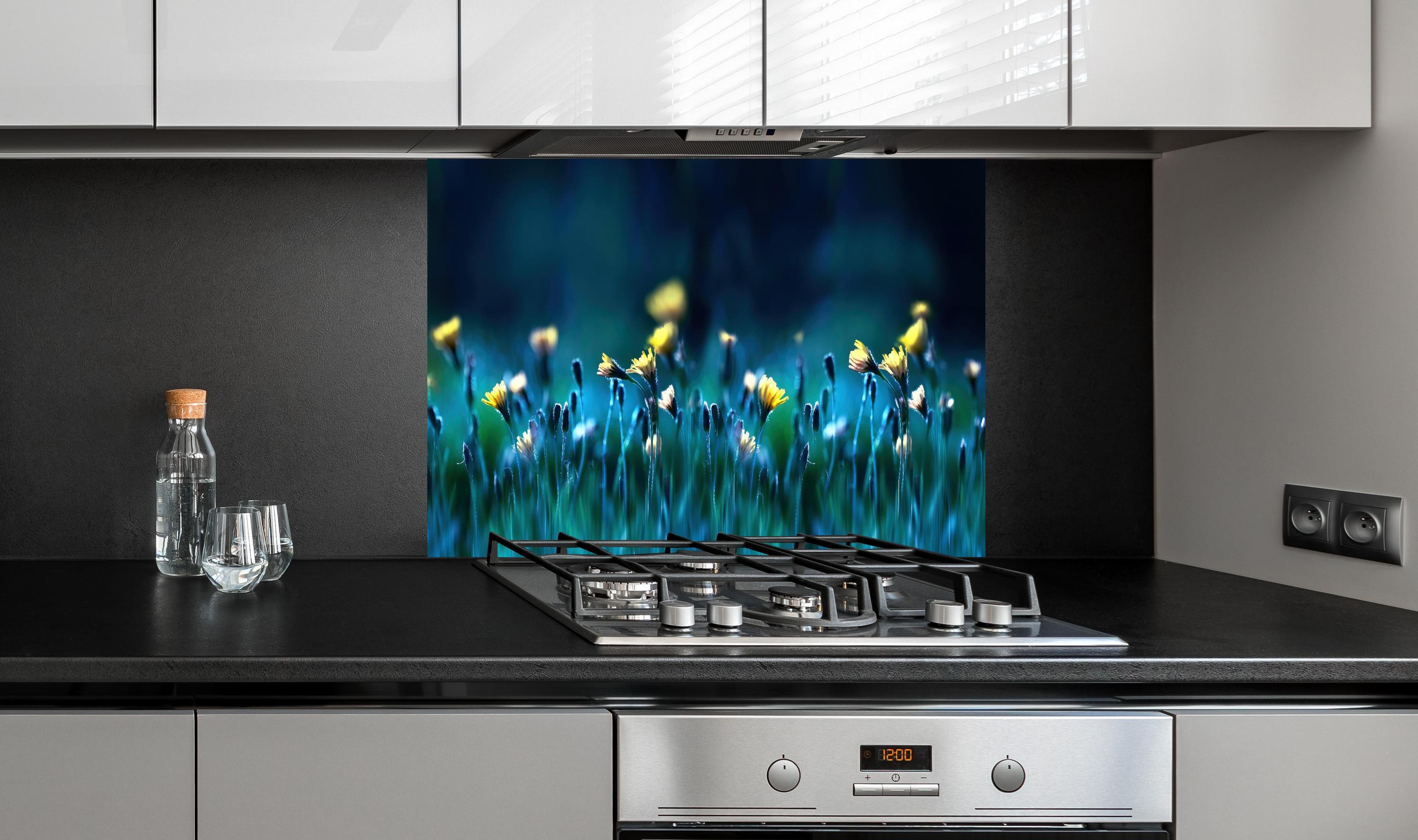 Spritzschutz - Leuchtende Blumen auf dunkelblauer Wiese hinter einem Cerankochfeld zwischen Holz-Kochutensilien