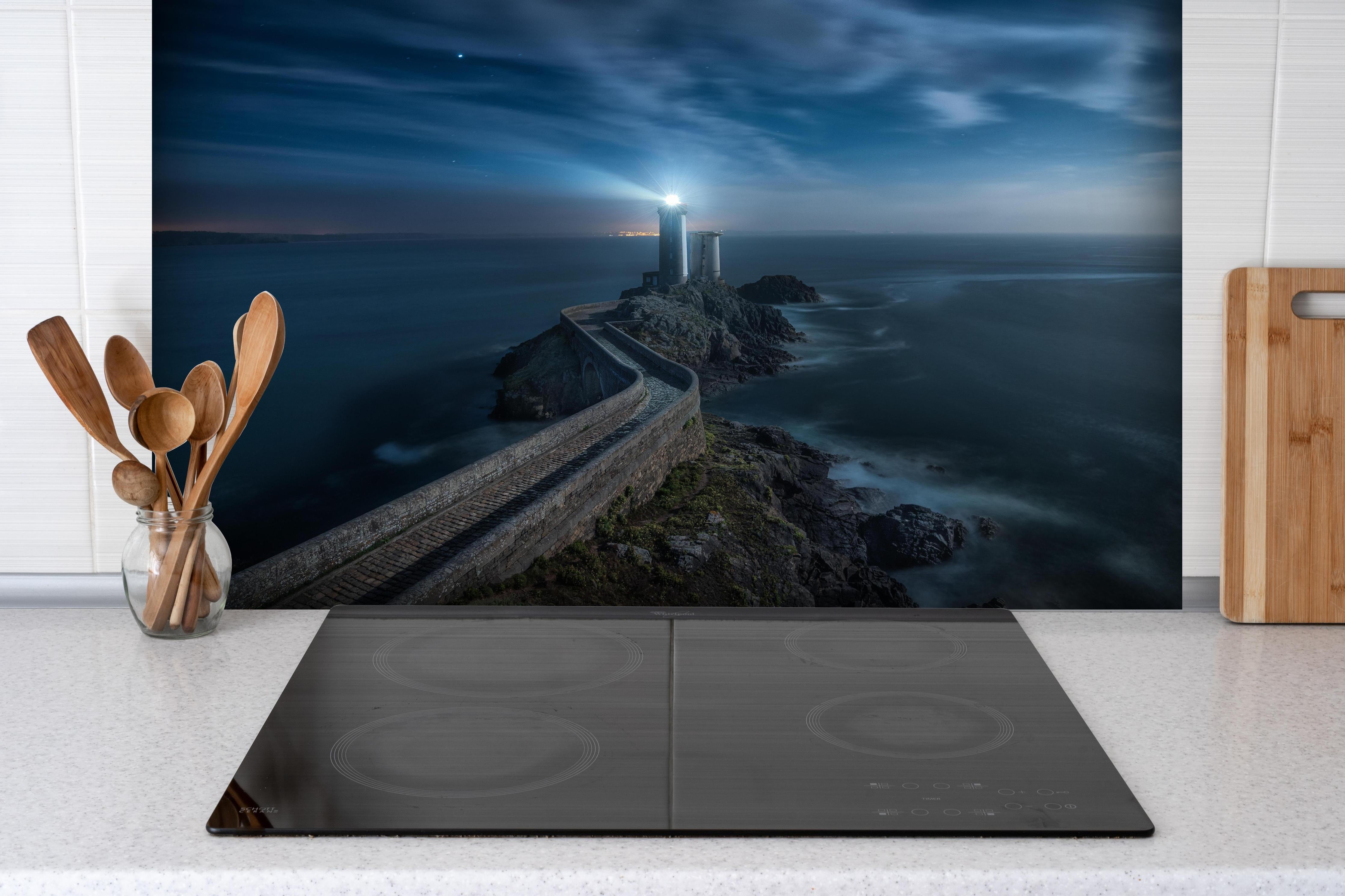 Spritzschutz - Leuchtturm - Nächtlich hinter einem Cerankochfeld zwischen Holz-Kochutensilien