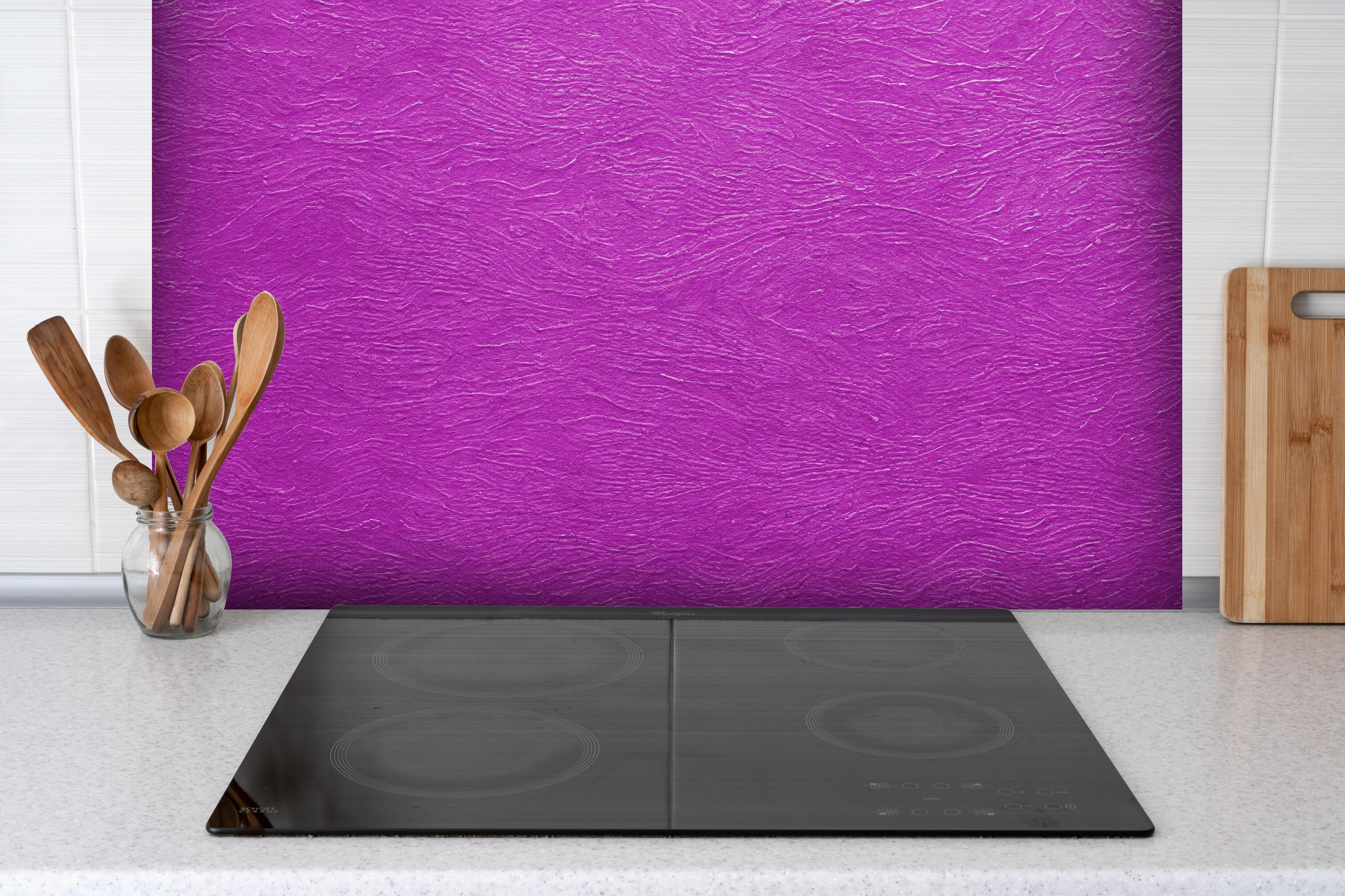 Spritzschutz - Lila Wandmuster hinter einem Cerankochfeld zwischen Holz-Kochutensilien