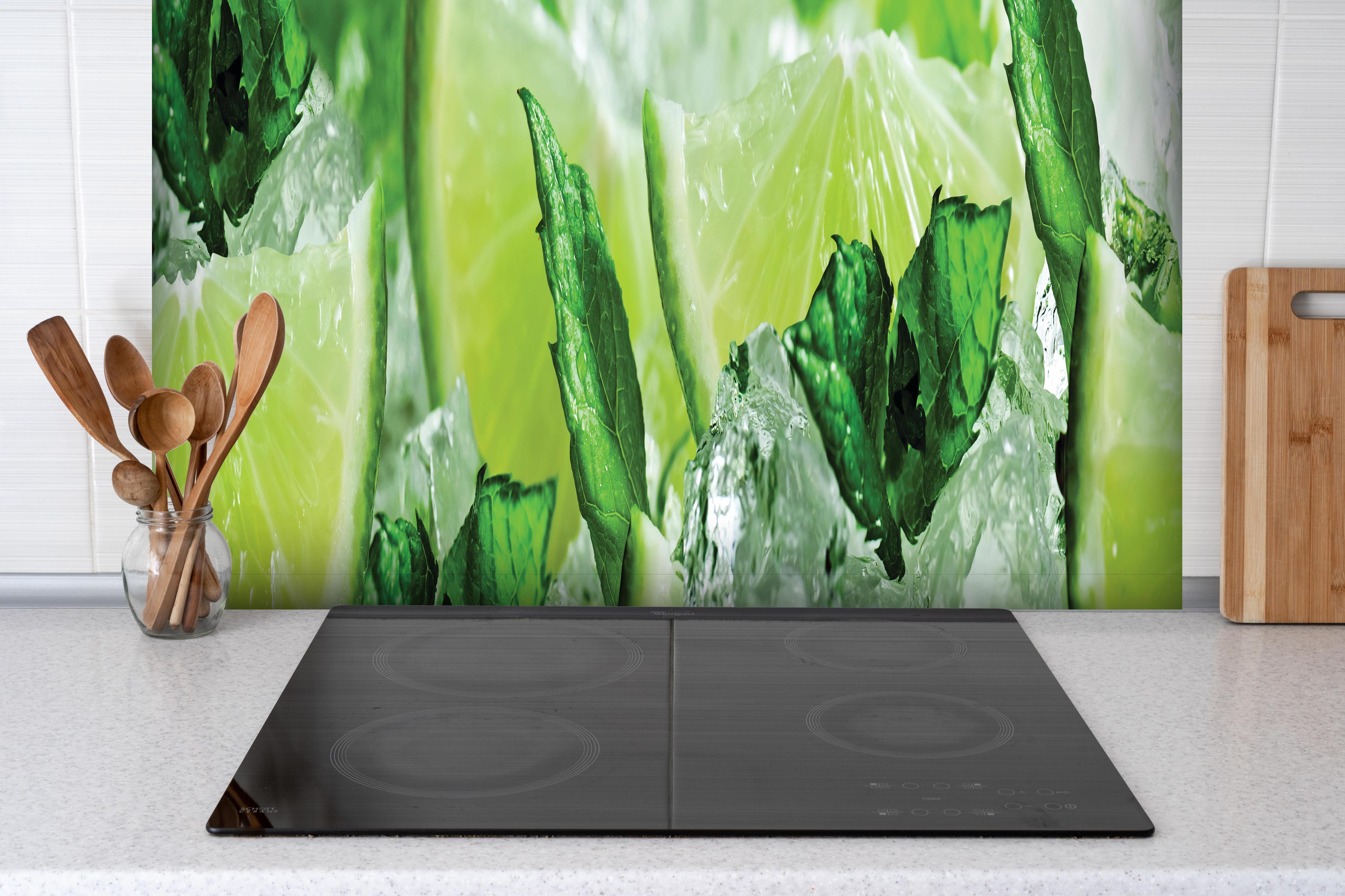Spritzschutz - Limette und Minzblätter mit Eis hinter einem Cerankochfeld zwischen Holz-Kochutensilien
