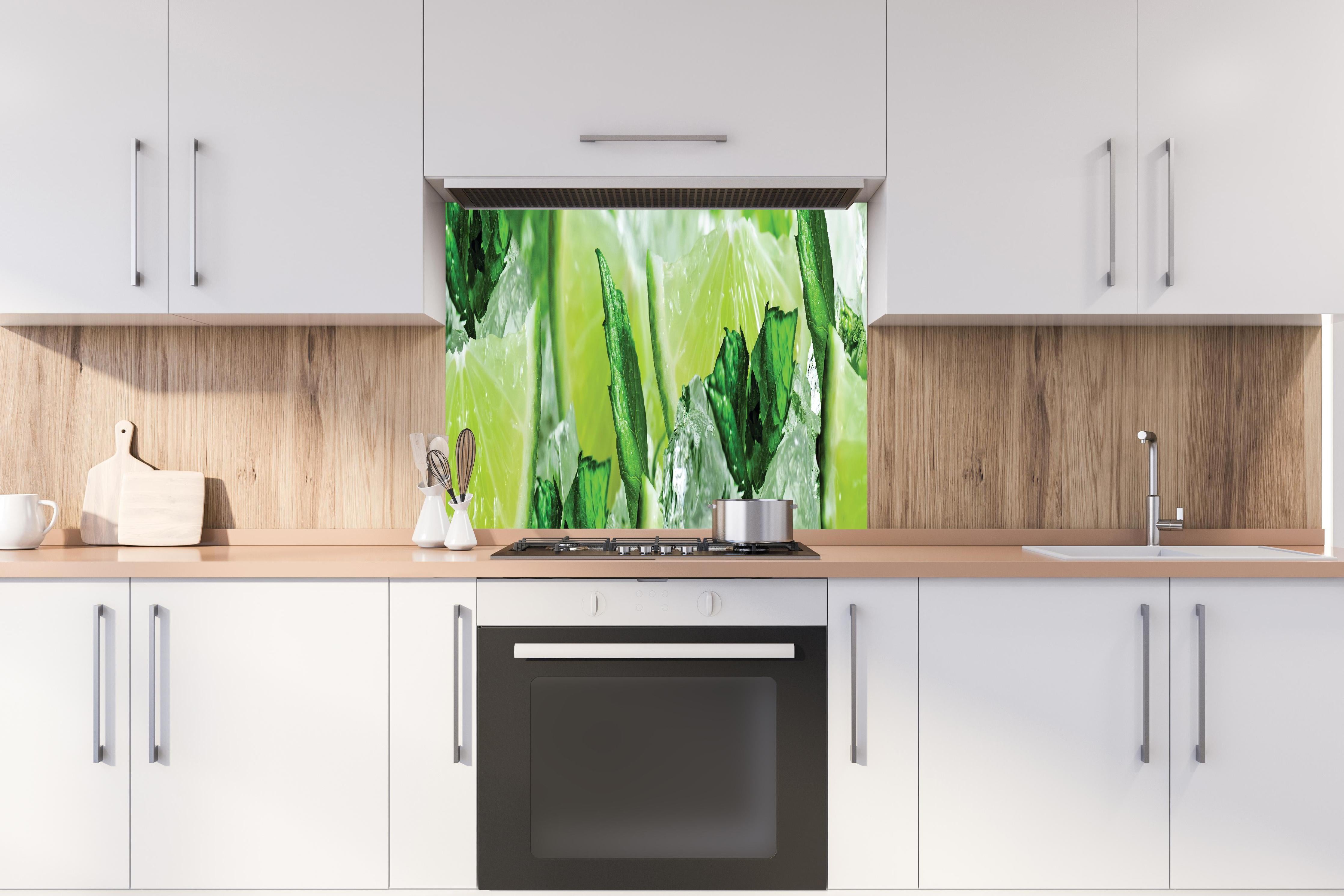 Spritzschutz - Limette und Minzblätter mit Eis hinter einem Cerankochfeld zwischen Holz-Kochutensilien