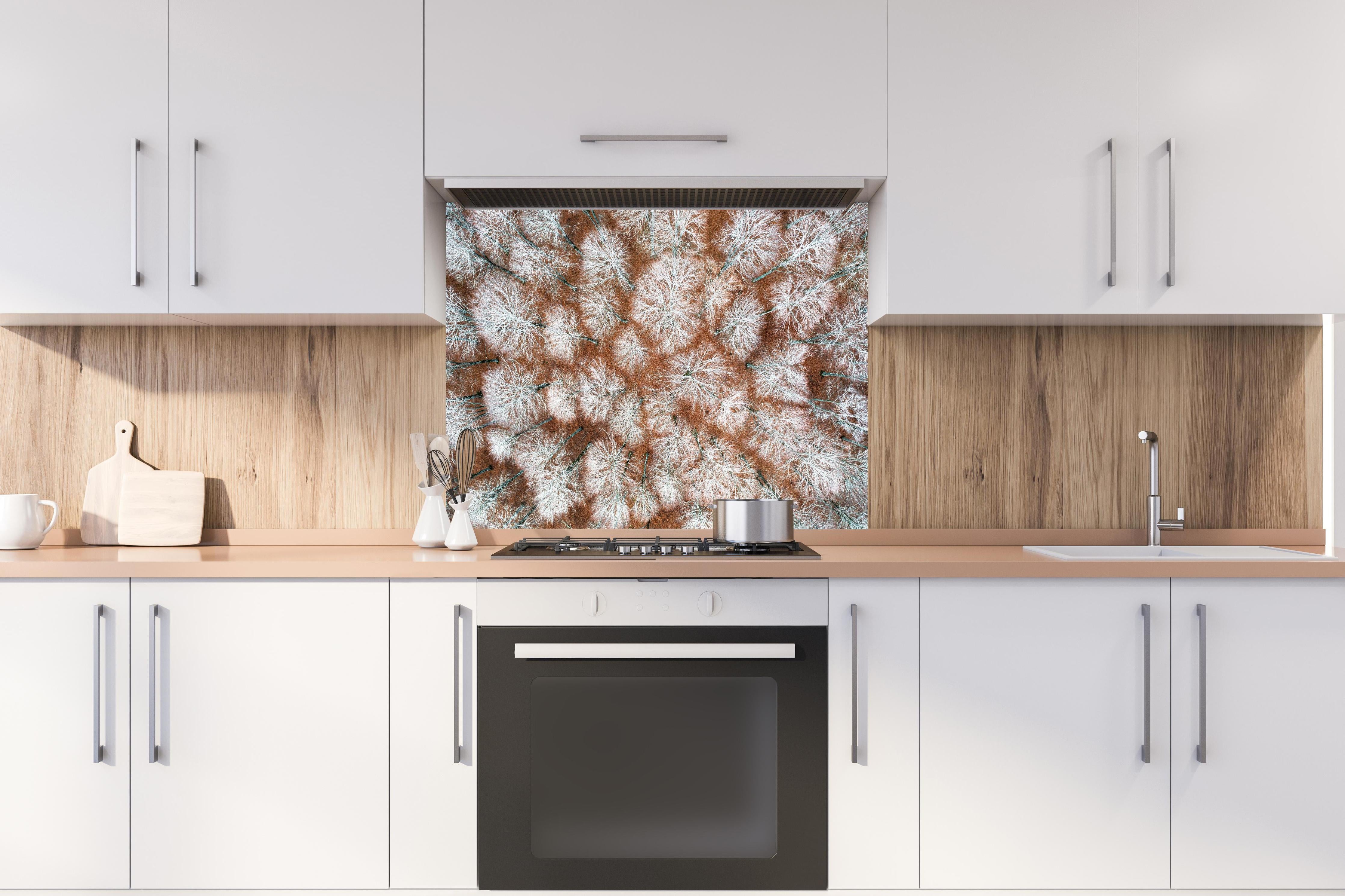 Spritzschutz - Luftansicht Herbstwald in Rot-Orange Tönen hinter einem Cerankochfeld zwischen Holz-Kochutensilien