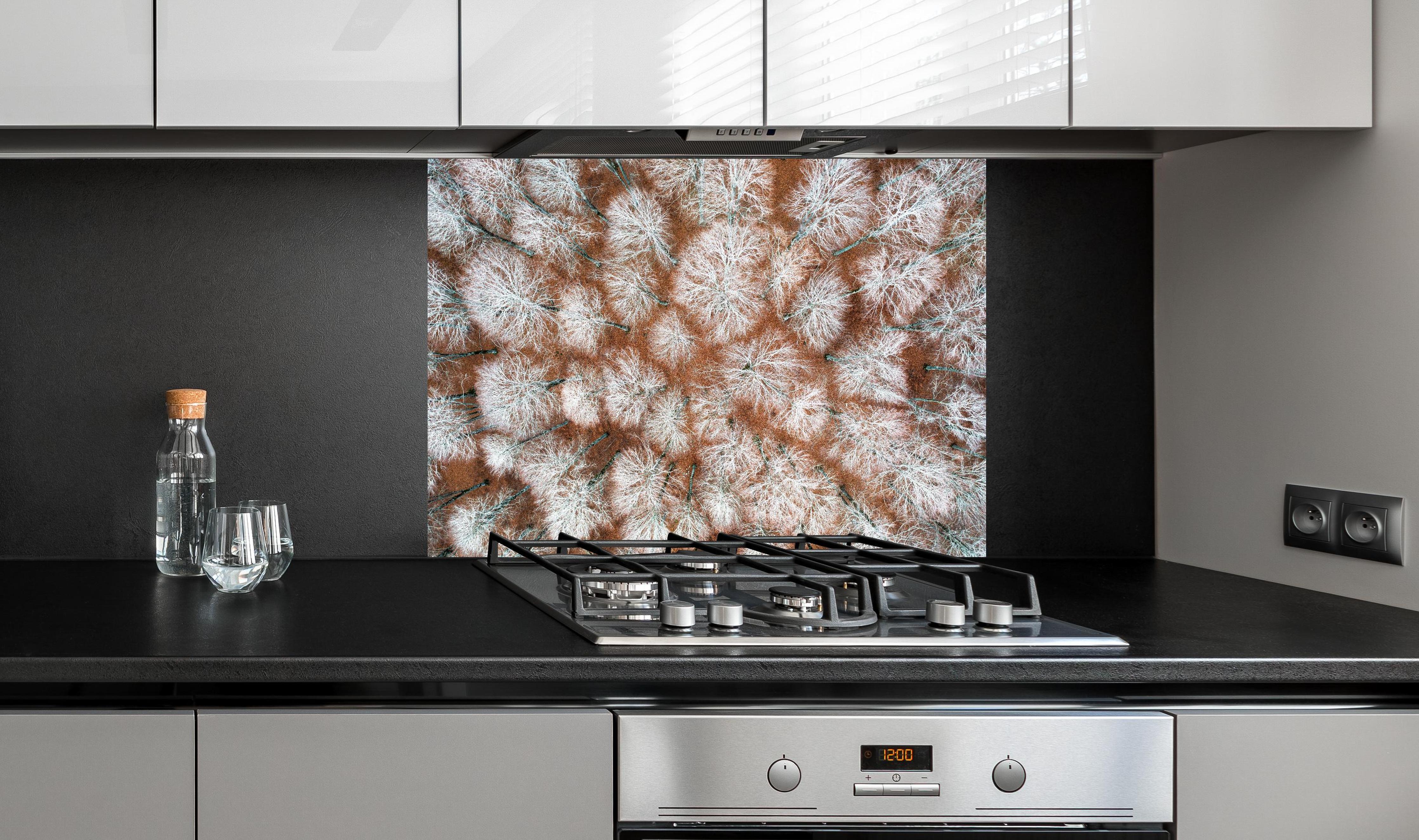 Spritzschutz - Luftansicht Herbstwald in Rot-Orange Tönen hinter einem Cerankochfeld zwischen Holz-Kochutensilien