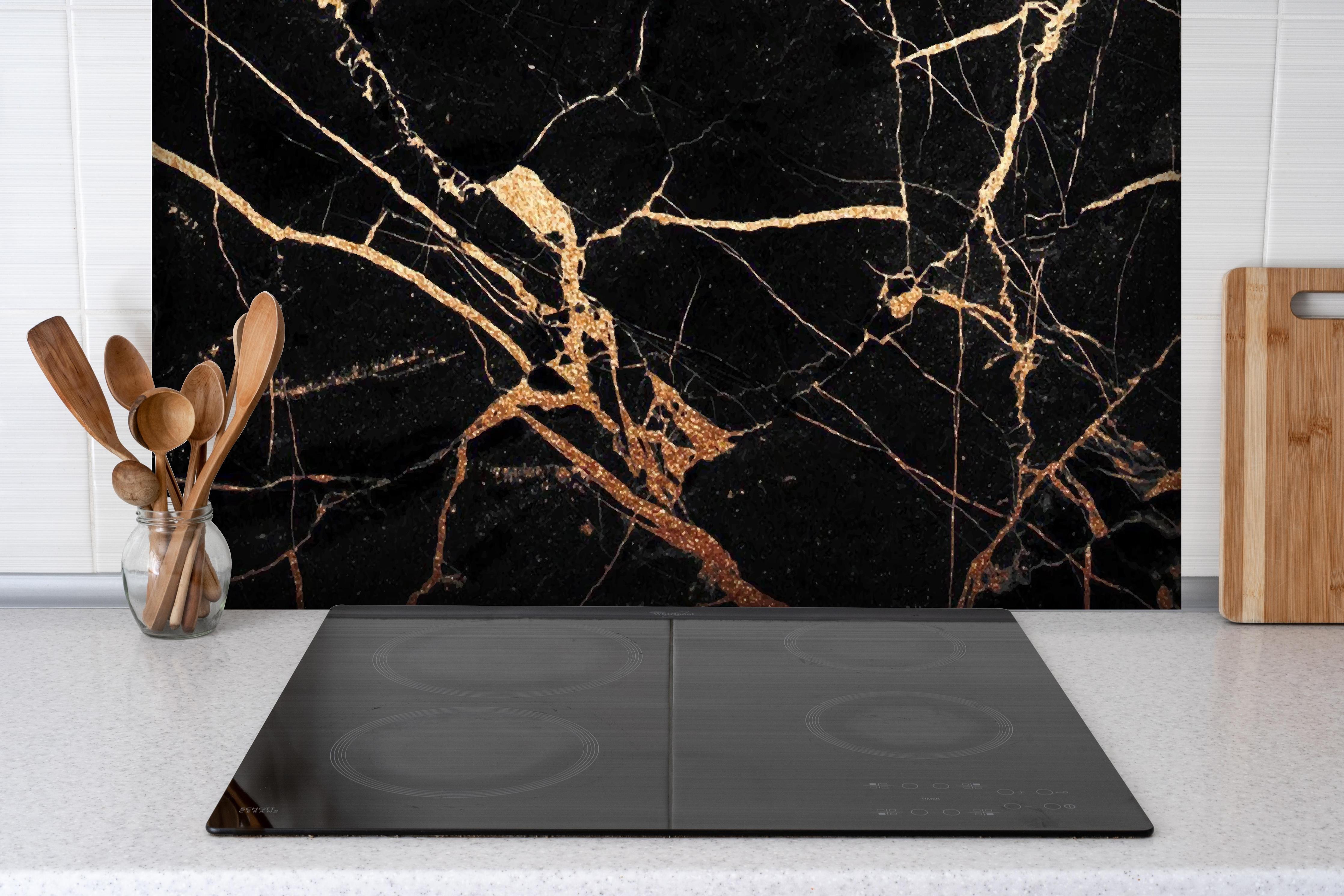 Spritzschutz - Luxus Goldene Ader Marmorstruktur Schwarz hinter einem Cerankochfeld zwischen Holz-Kochutensilien