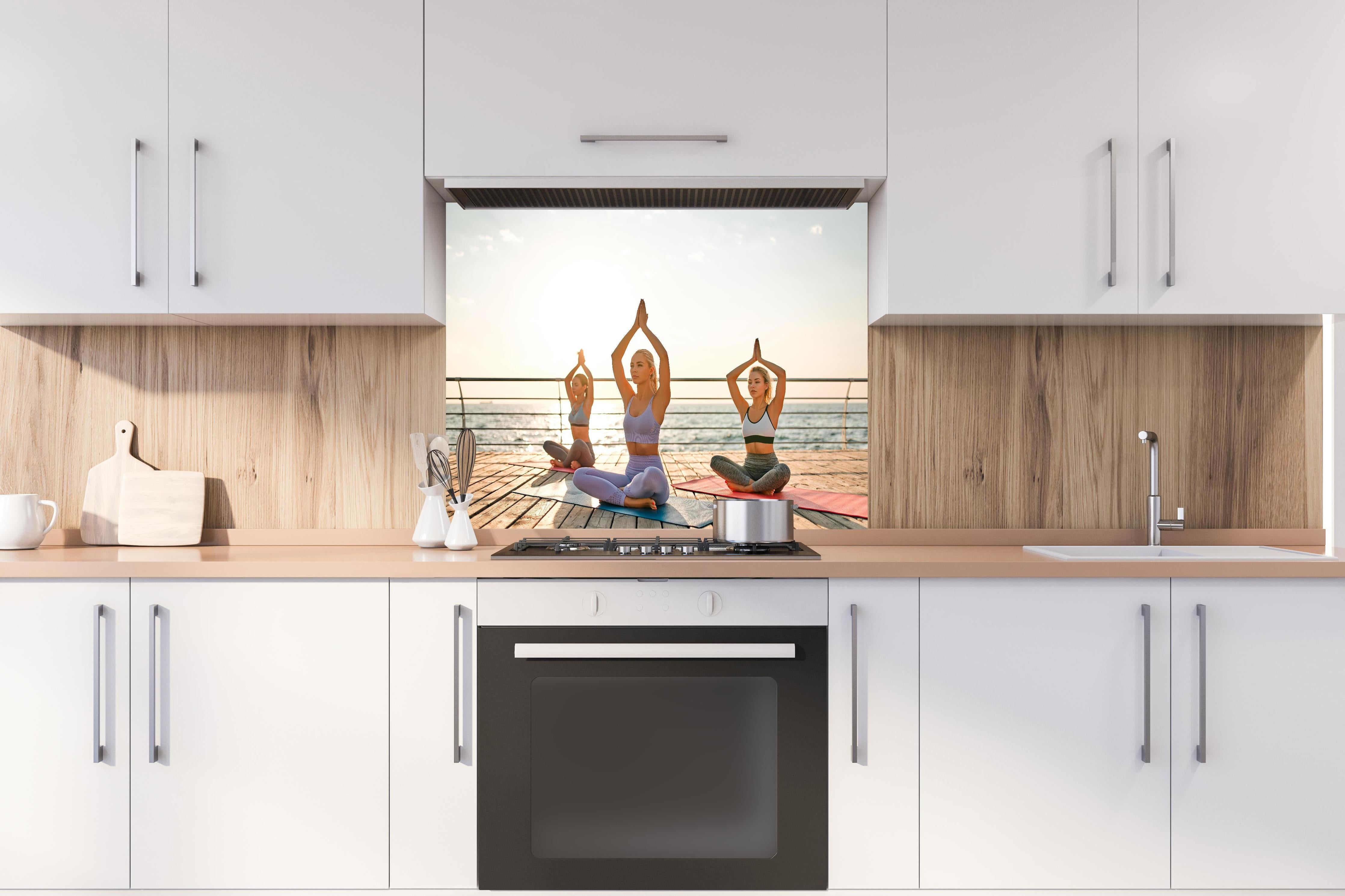 Spritzschutz - Mädchen beim Yoga am Morgen hinter einem Cerankochfeld zwischen Holz-Kochutensilien