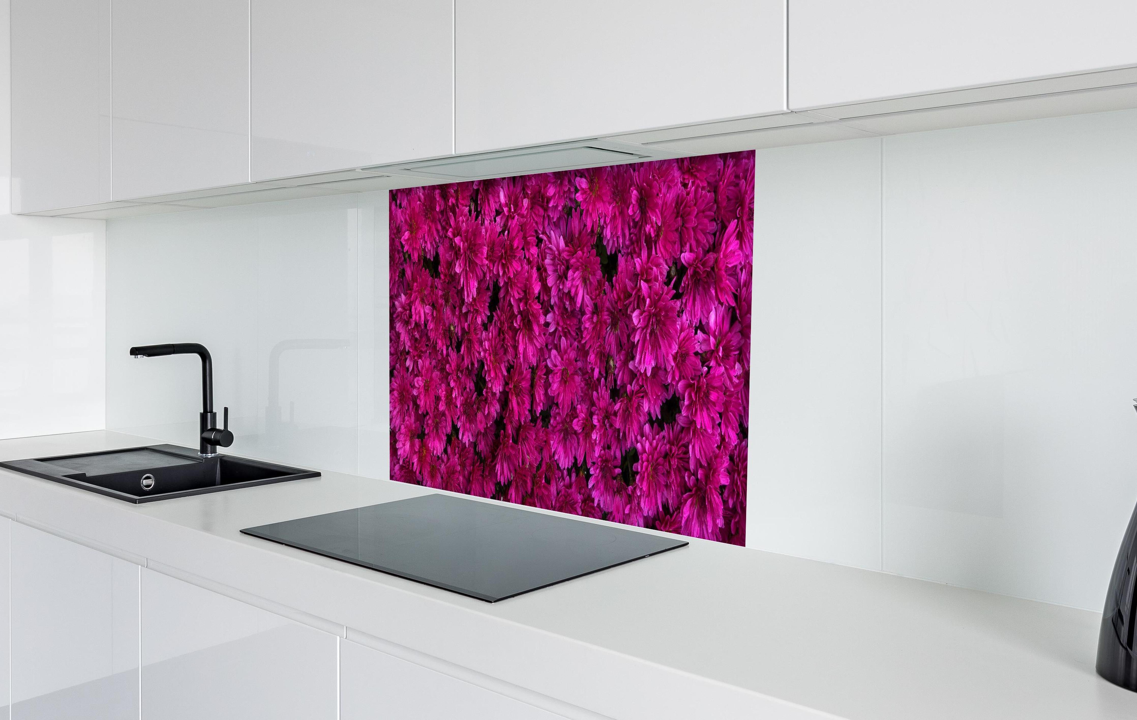 Spritzschutz - Magenta Blüten von Chrysanthemen hinter einem Cerankochfeld zwischen Holz-Kochutensilien