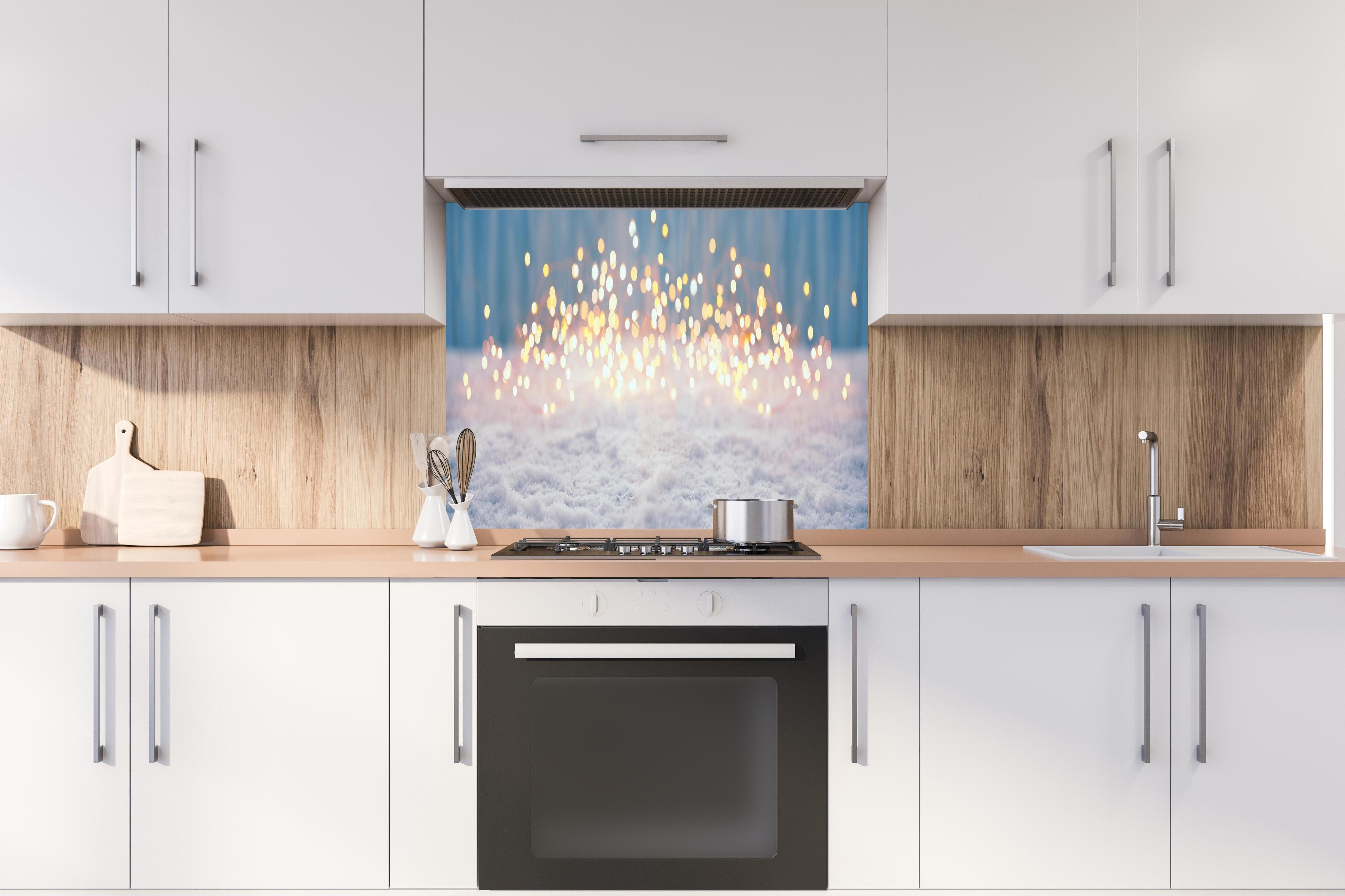 Spritzschutz - Magische Winterlandschaft mit goldenem Bokeh hinter einem Cerankochfeld zwischen Holz-Kochutensilien