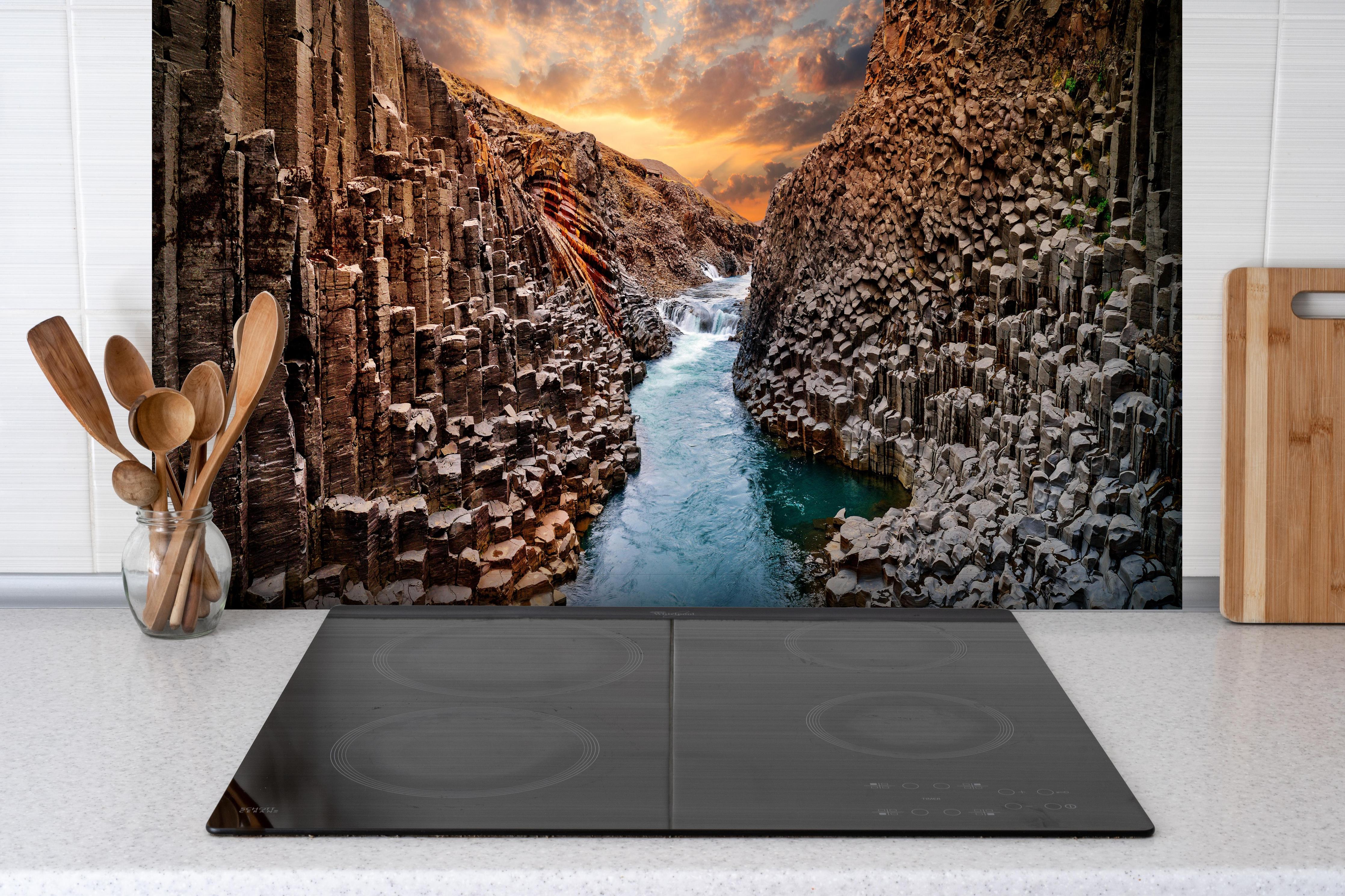Spritzschutz - Majestätische Basalt-Schlucht Island Sonnenuntergang hinter einem Cerankochfeld zwischen Holz-Kochutensilien