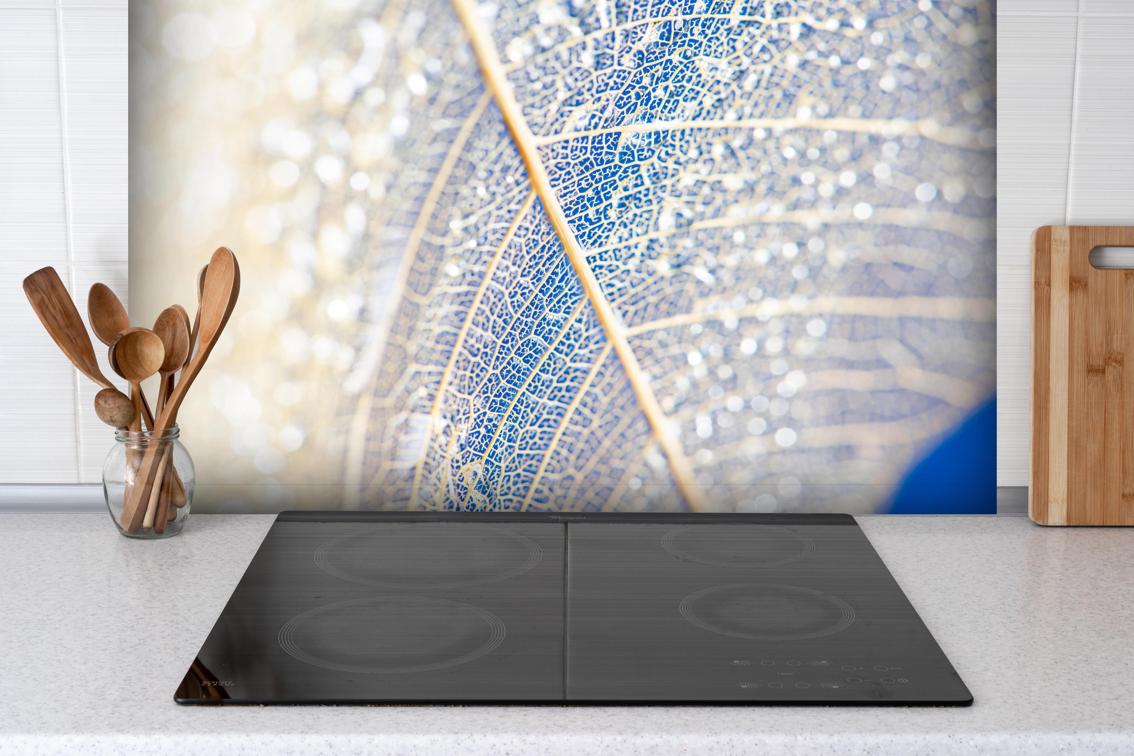 Spritzschutz - Makro Fotografie eines skelettierten Blattes hinter einem Cerankochfeld zwischen Holz-Kochutensilien