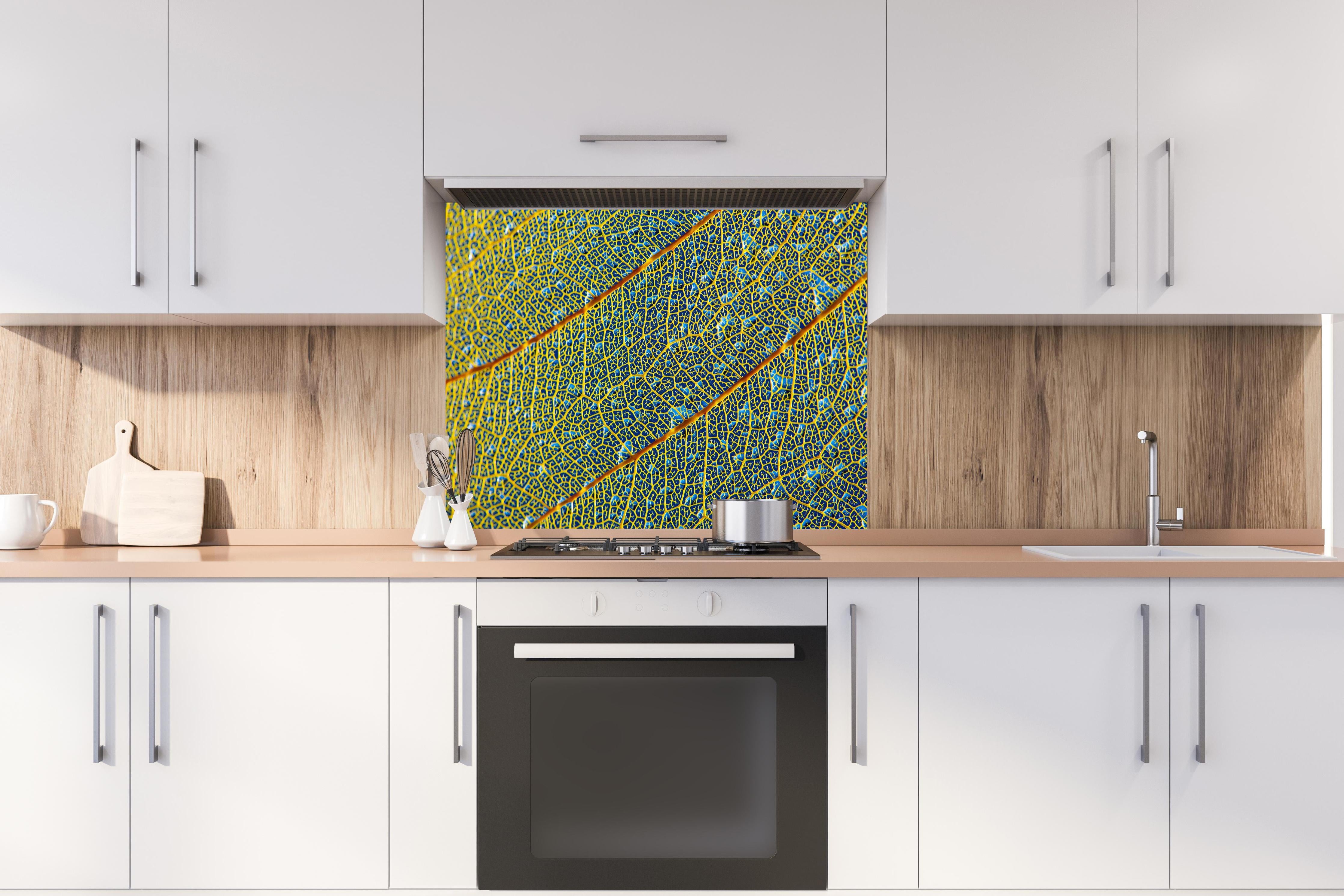 Spritzschutz - Makroaufnahme Gelbes Blatt mit Adern hinter einem Cerankochfeld zwischen Holz-Kochutensilien