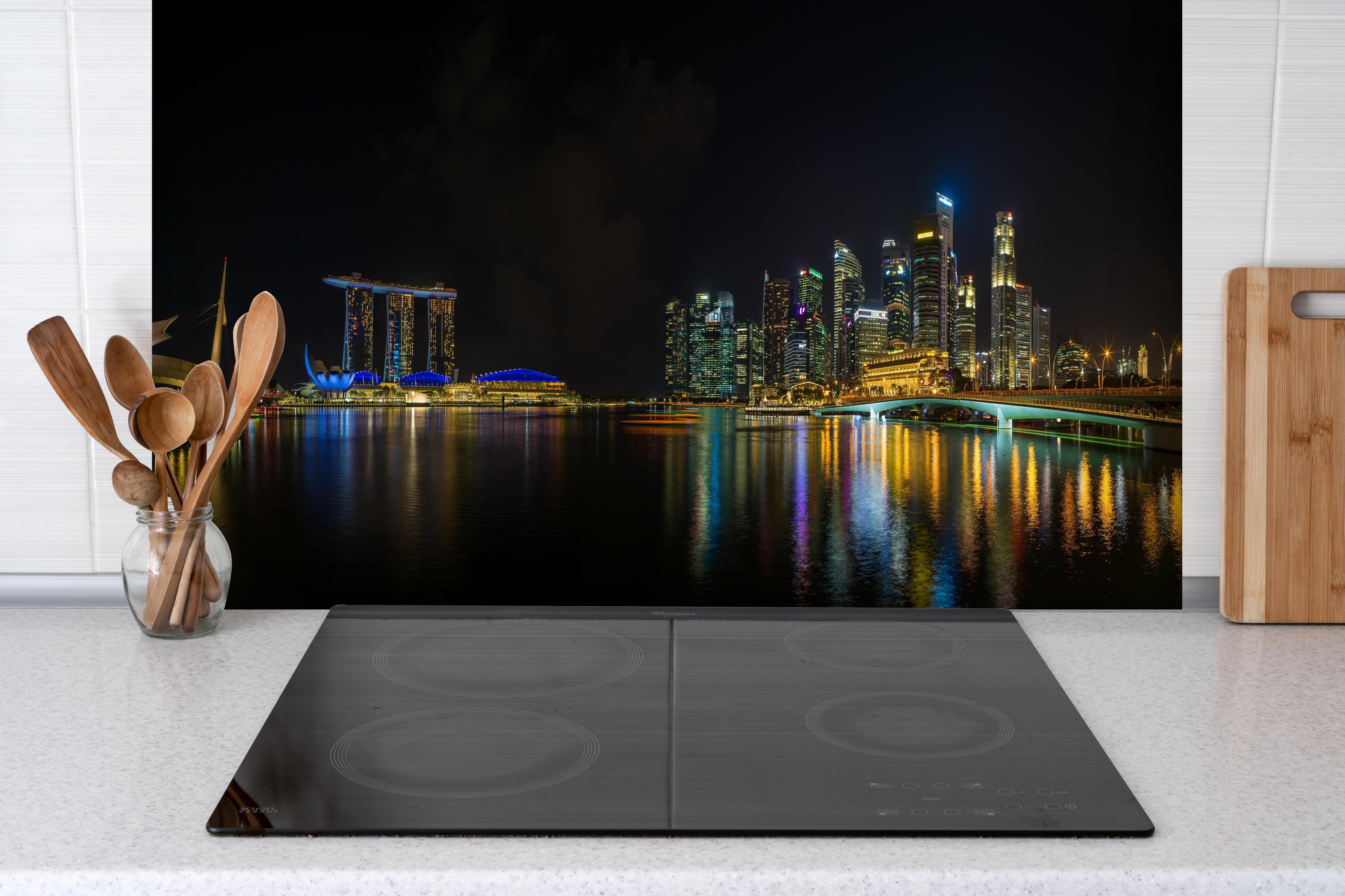 Spritzschutz - Marina Bay Sands bei Nacht hinter einem Cerankochfeld zwischen Holz-Kochutensilien
