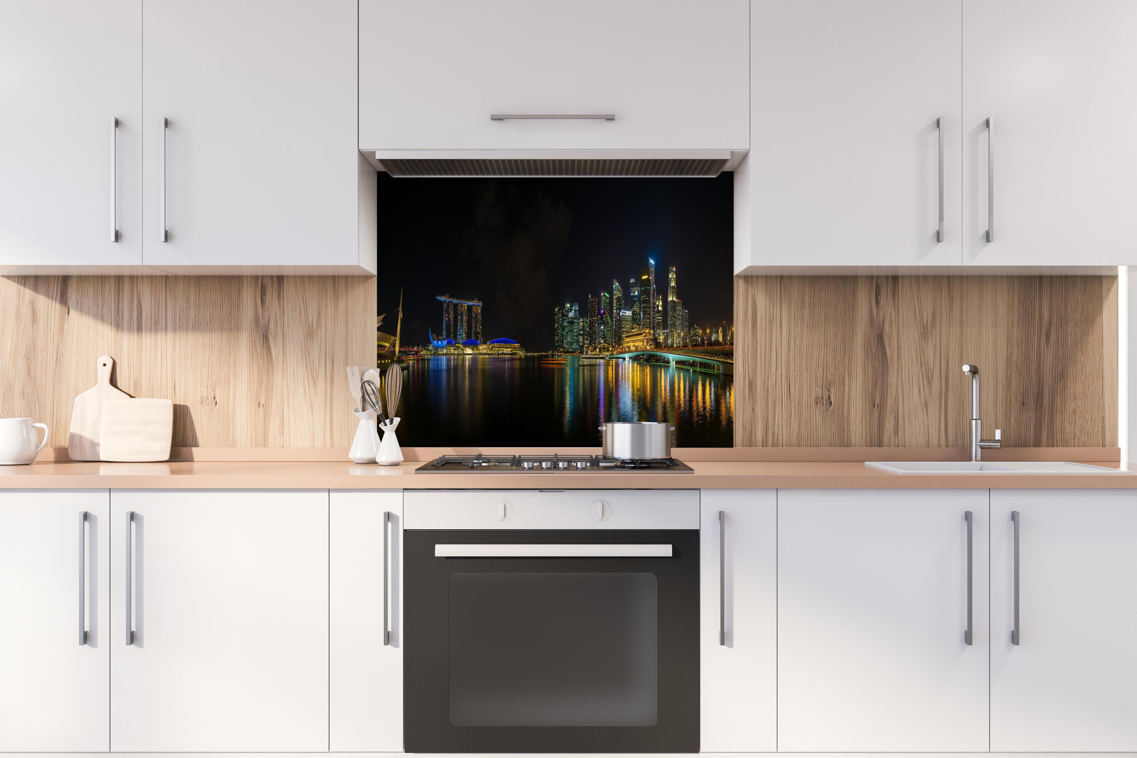 Spritzschutz - Marina Bay Sands bei Nacht hinter einem Cerankochfeld zwischen Holz-Kochutensilien