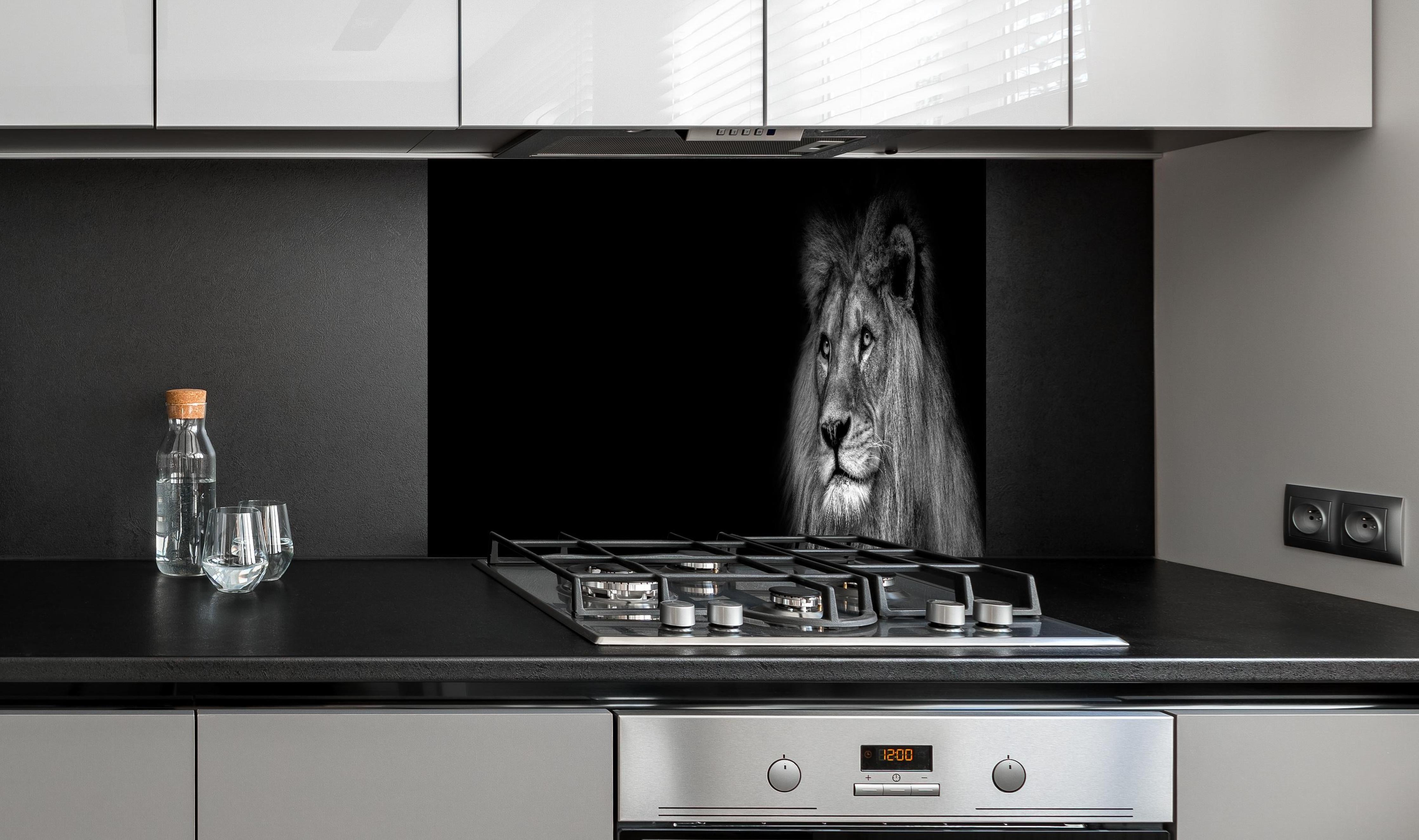 Spritzschutz - Markantes Löwen Gesicht Schwarz-Weiß hinter einem Cerankochfeld zwischen Holz-Kochutensilien