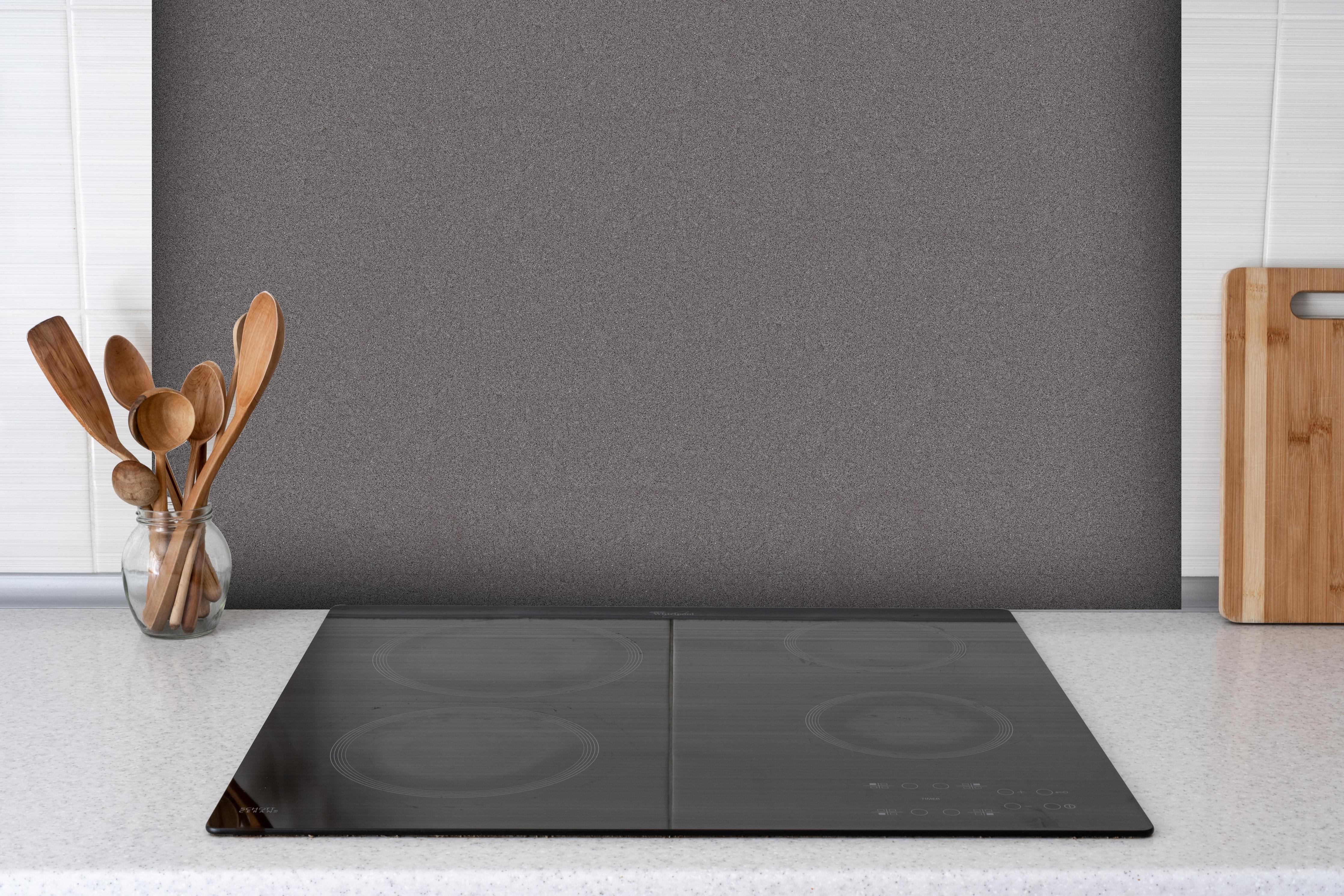 Spritzschutz - Marmor Textur dunkel hinter einem Cerankochfeld zwischen Holz-Kochutensilien