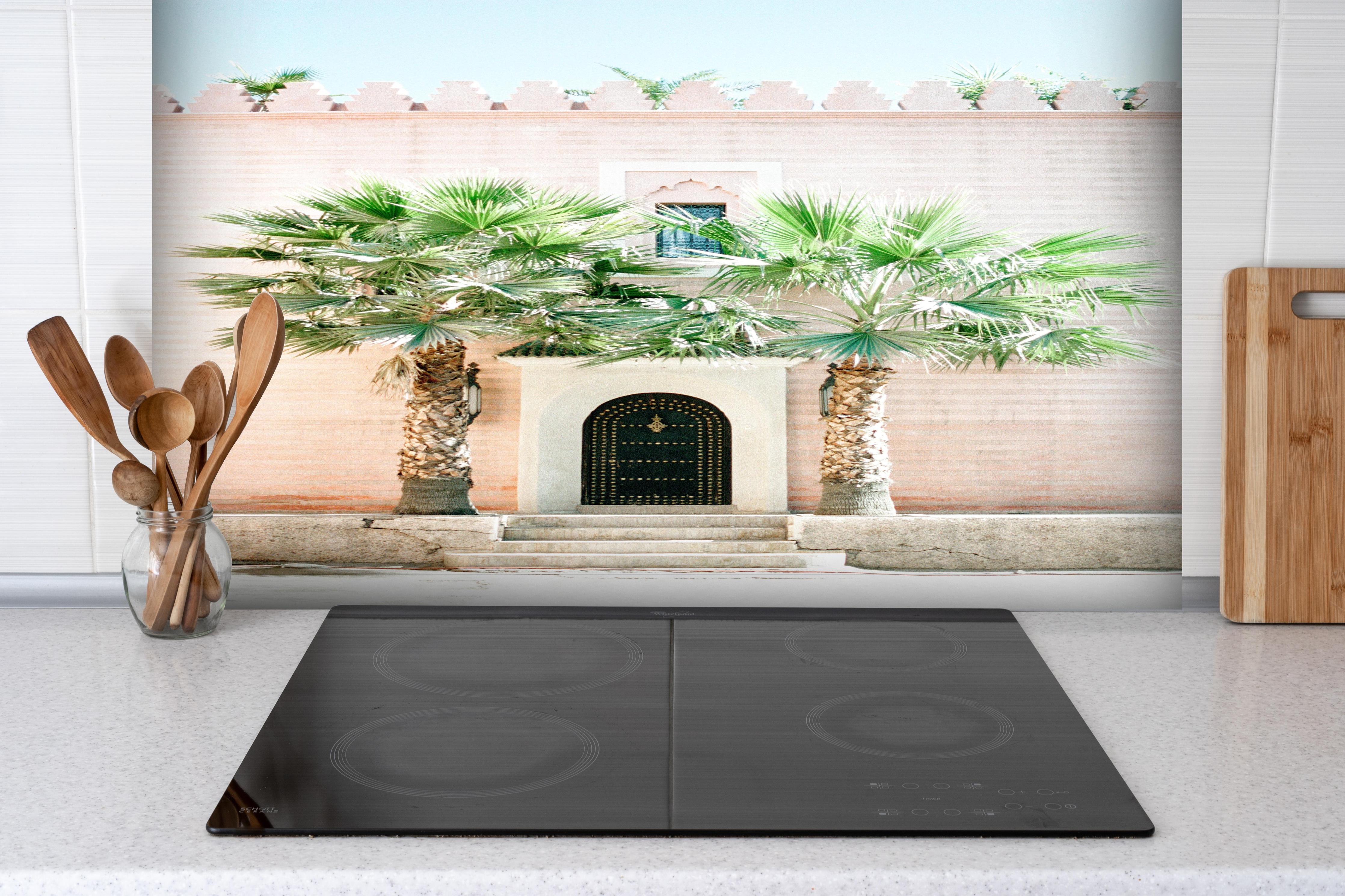 Spritzschutz - Marokkanische Palmentür in Rosa hinter einem Cerankochfeld zwischen Holz-Kochutensilien