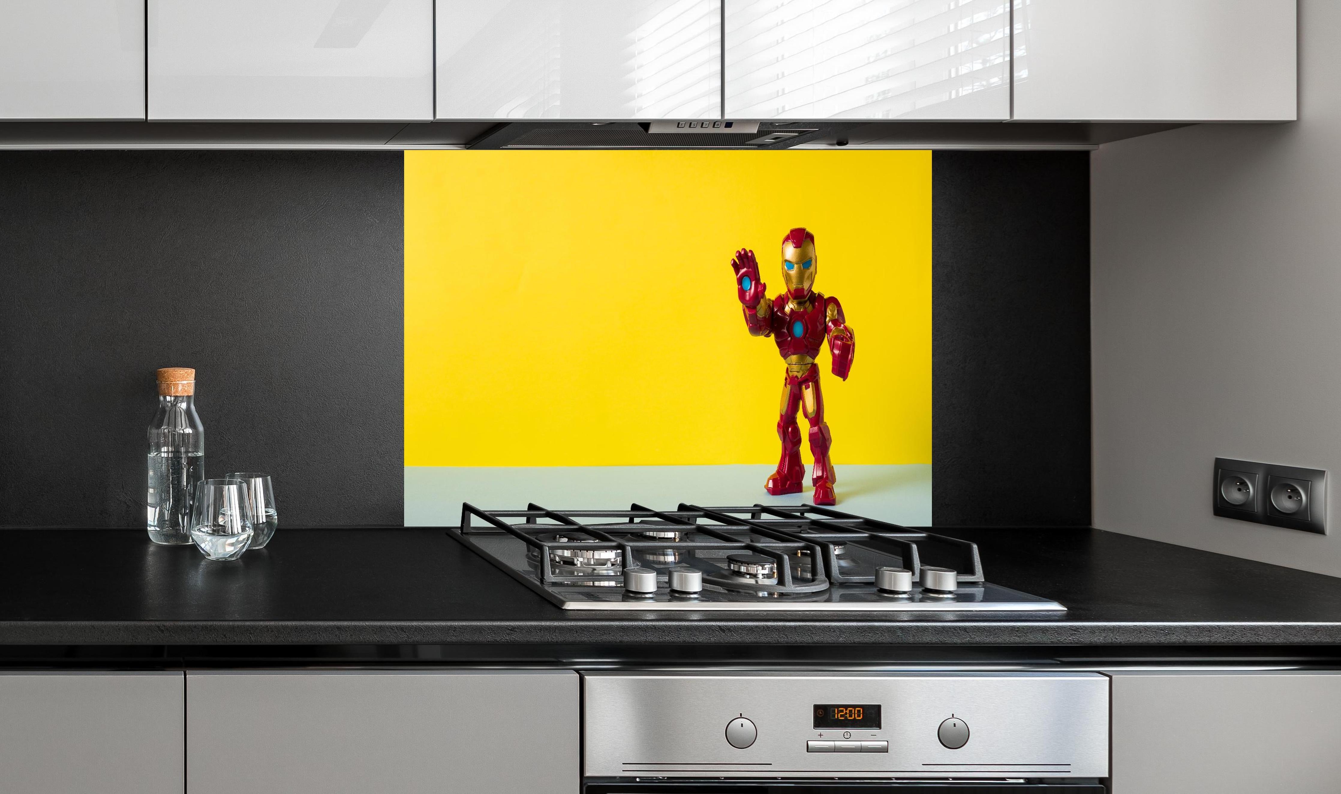 Spritzschutz - Marvel Iron Man Sammelfigur auf Gelb hinter einem Cerankochfeld zwischen Holz-Kochutensilien