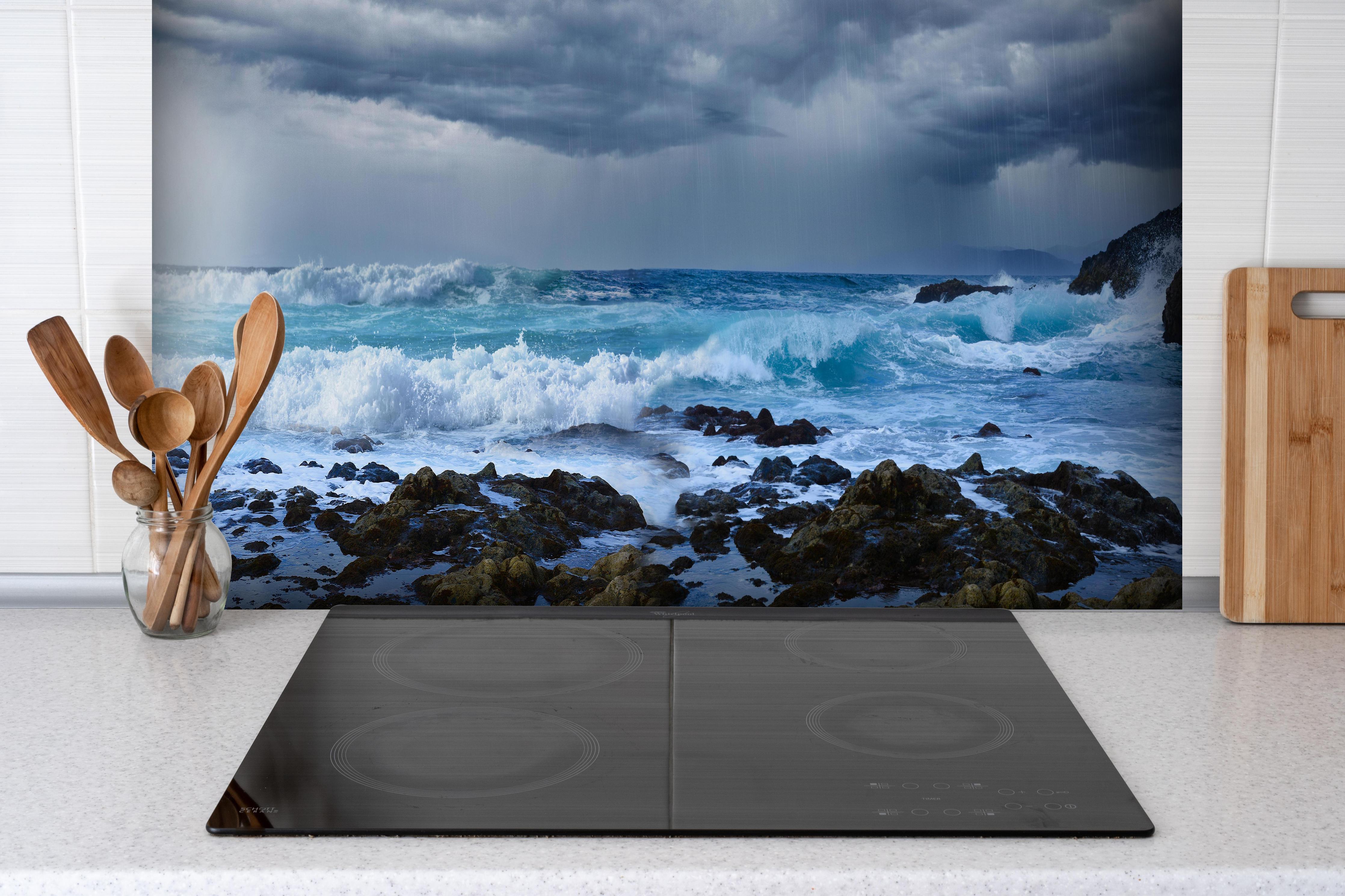Spritzschutz - Meeresküste mit dunklen Regenwolken und stürmischer See hinter einem Cerankochfeld zwischen Holz-Kochutensilien