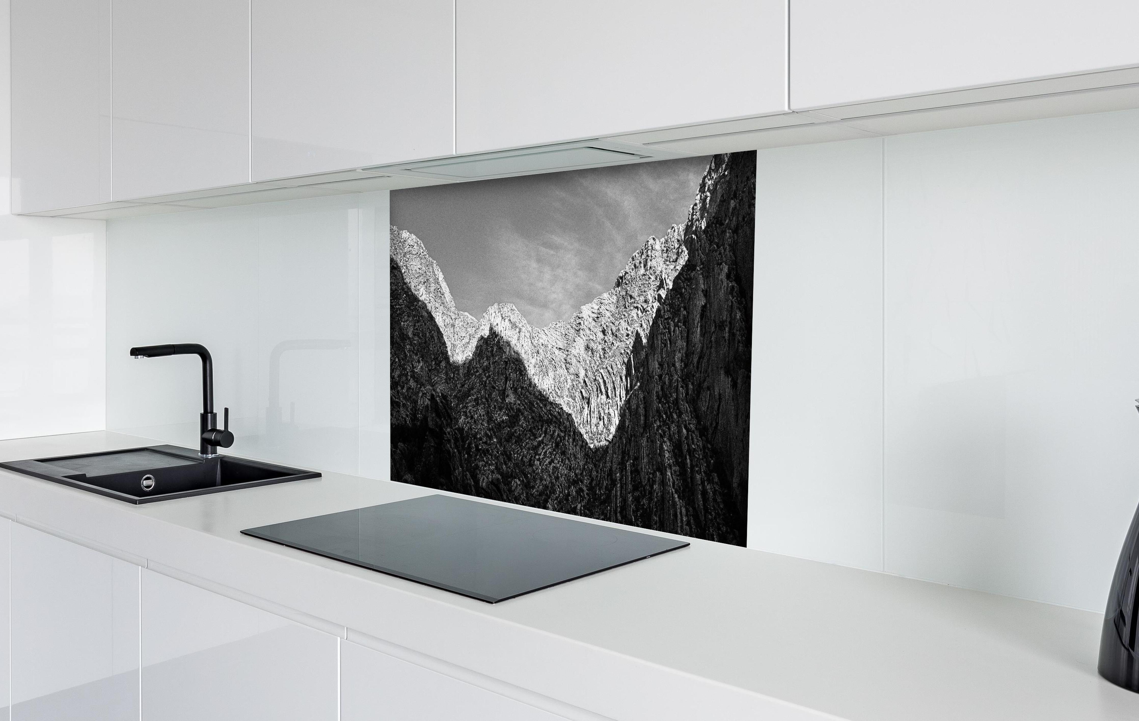 Spritzschutz - Minimalistische Berglandschaft in Schwarz-Weiß hinter einem Cerankochfeld zwischen Holz-Kochutensilien