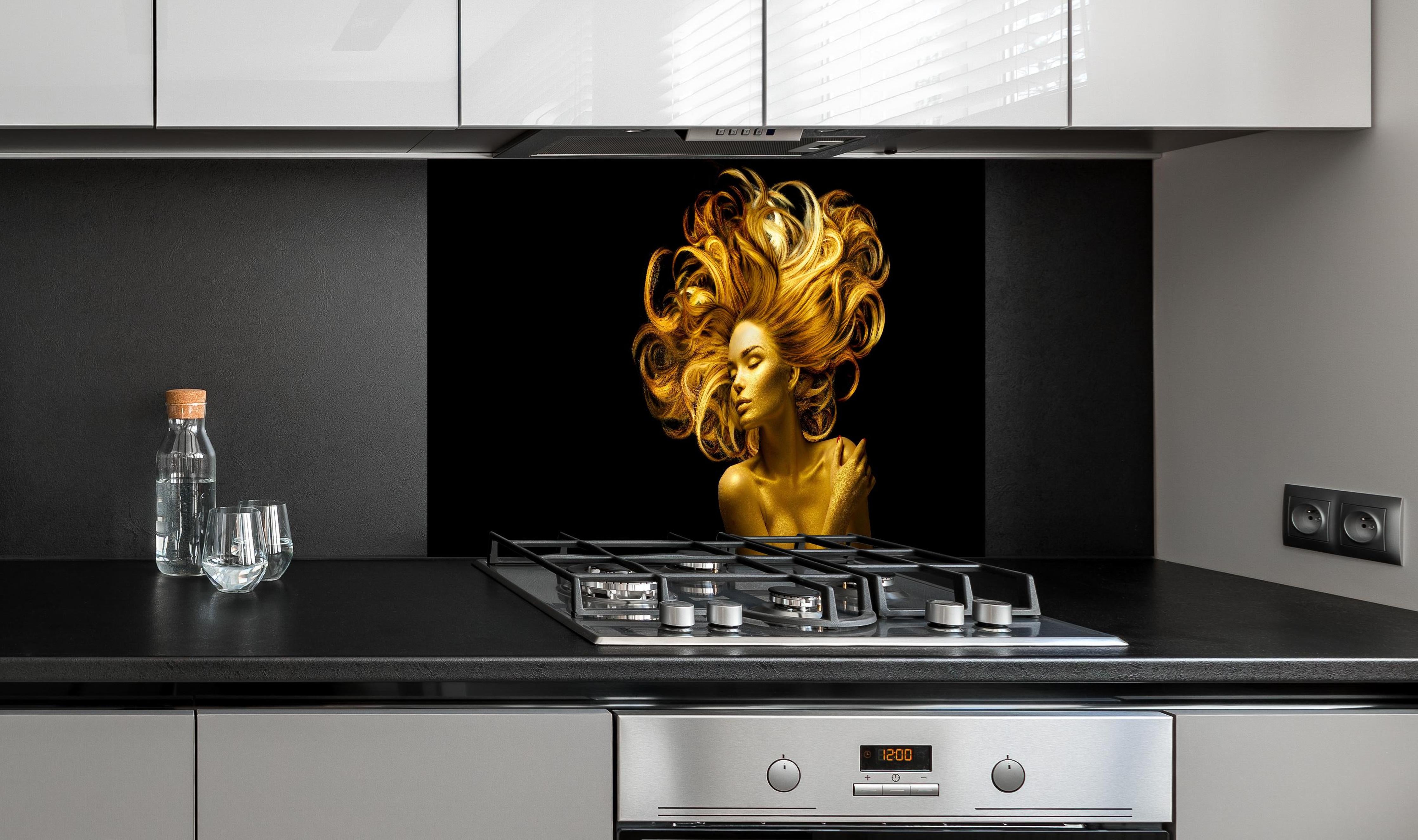 Spritzschutz - Model in Gold hinter einem Cerankochfeld zwischen Holz-Kochutensilien