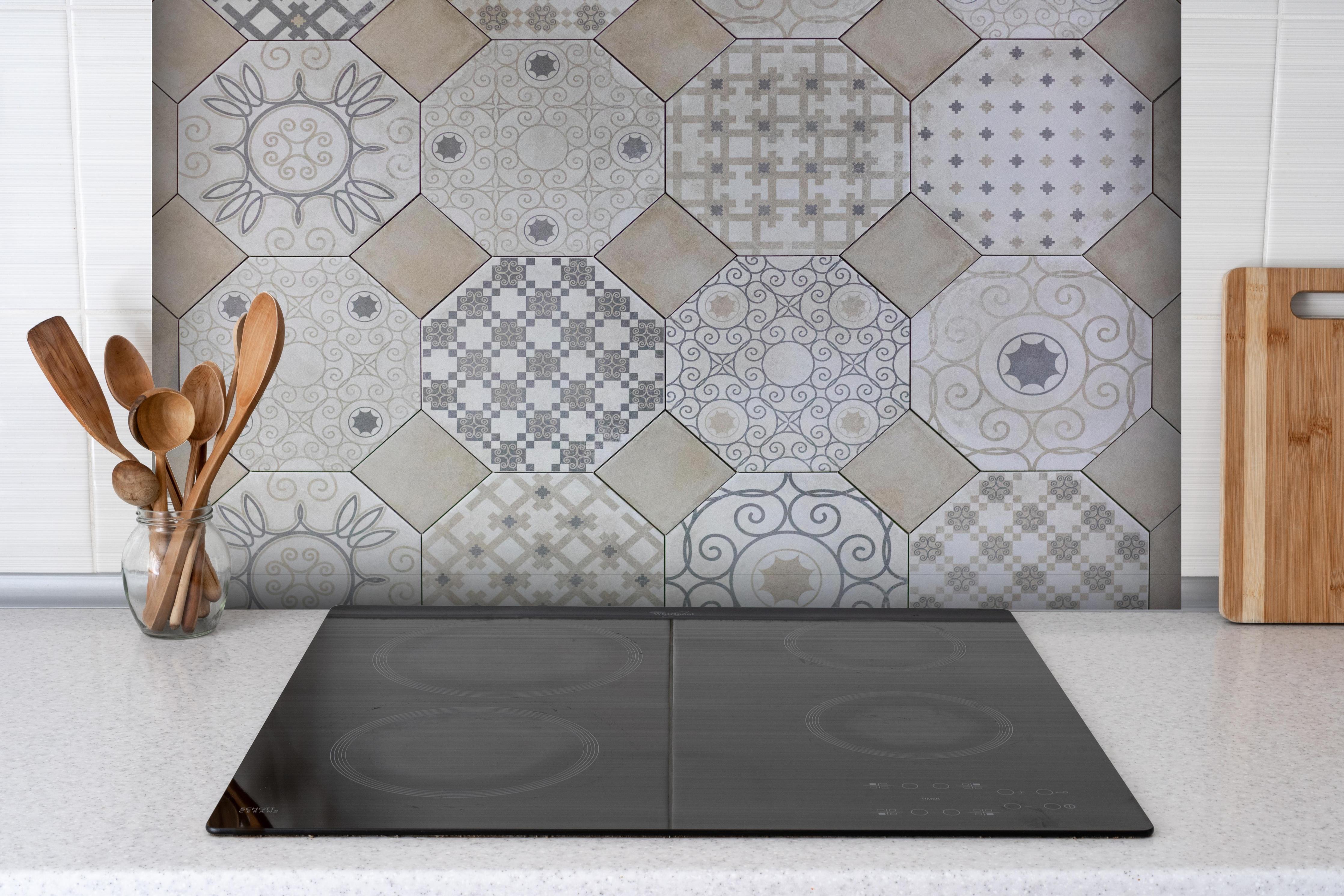 Spritzschutz - Moderne Hexagon-Fliesen in Weiß und Grau hinter einem Cerankochfeld zwischen Holz-Kochutensilien