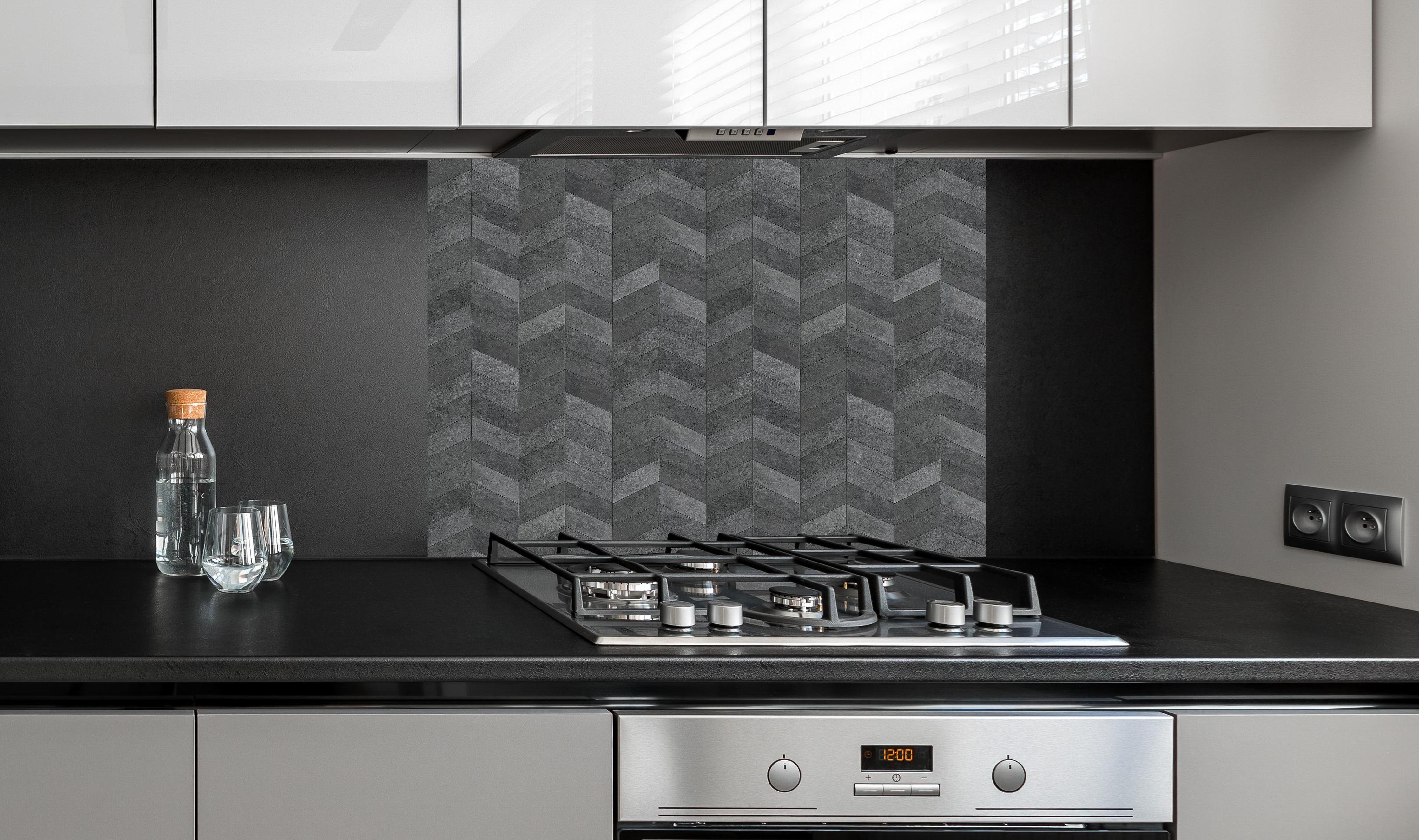 Spritzschutz - Moderne graue Chevron-Wandtextur hinter einem Cerankochfeld zwischen Holz-Kochutensilien