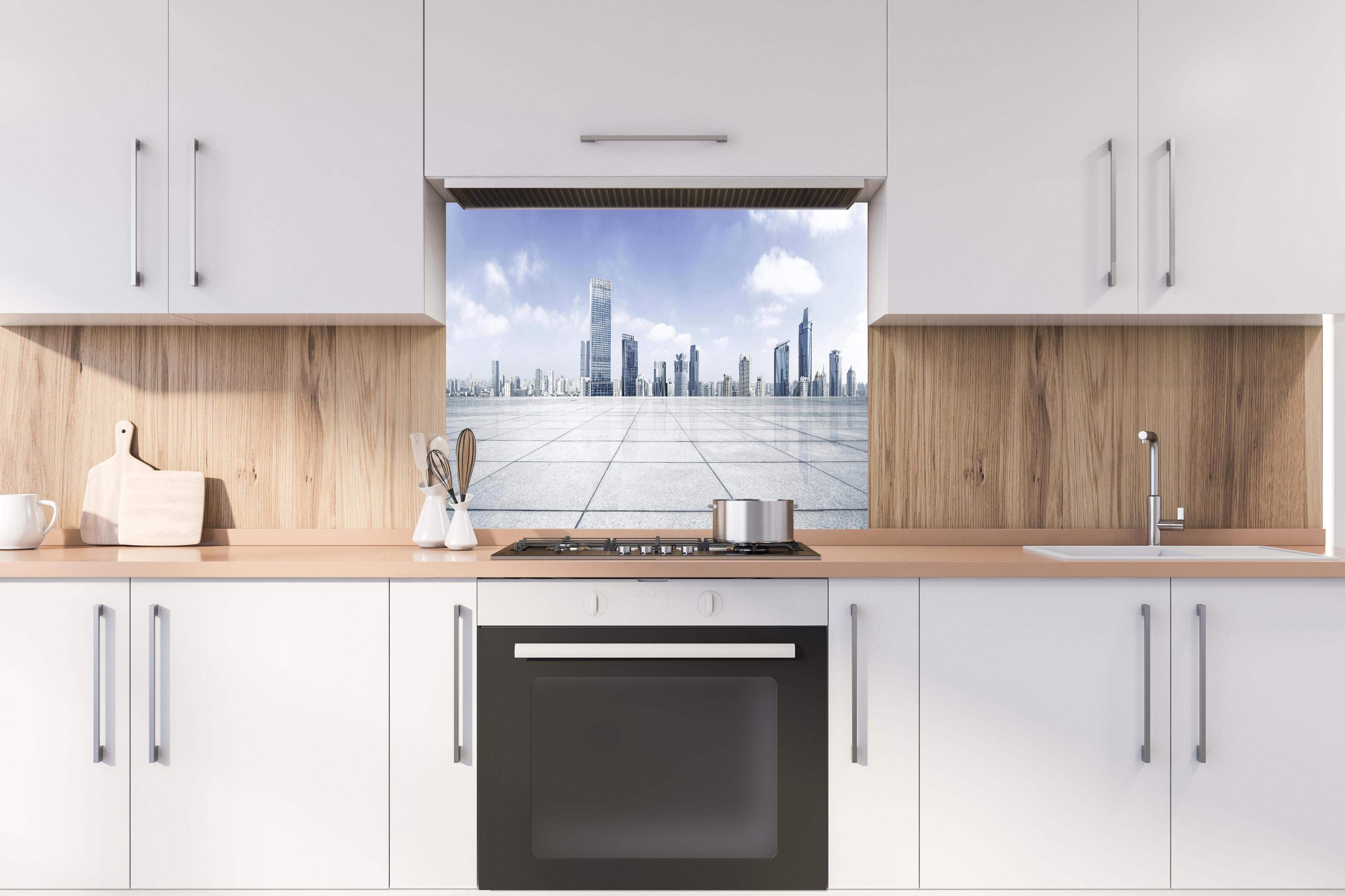 Spritzschutz - Moderner Skyline und Gebäuden hinter einem Cerankochfeld zwischen Holz-Kochutensilien