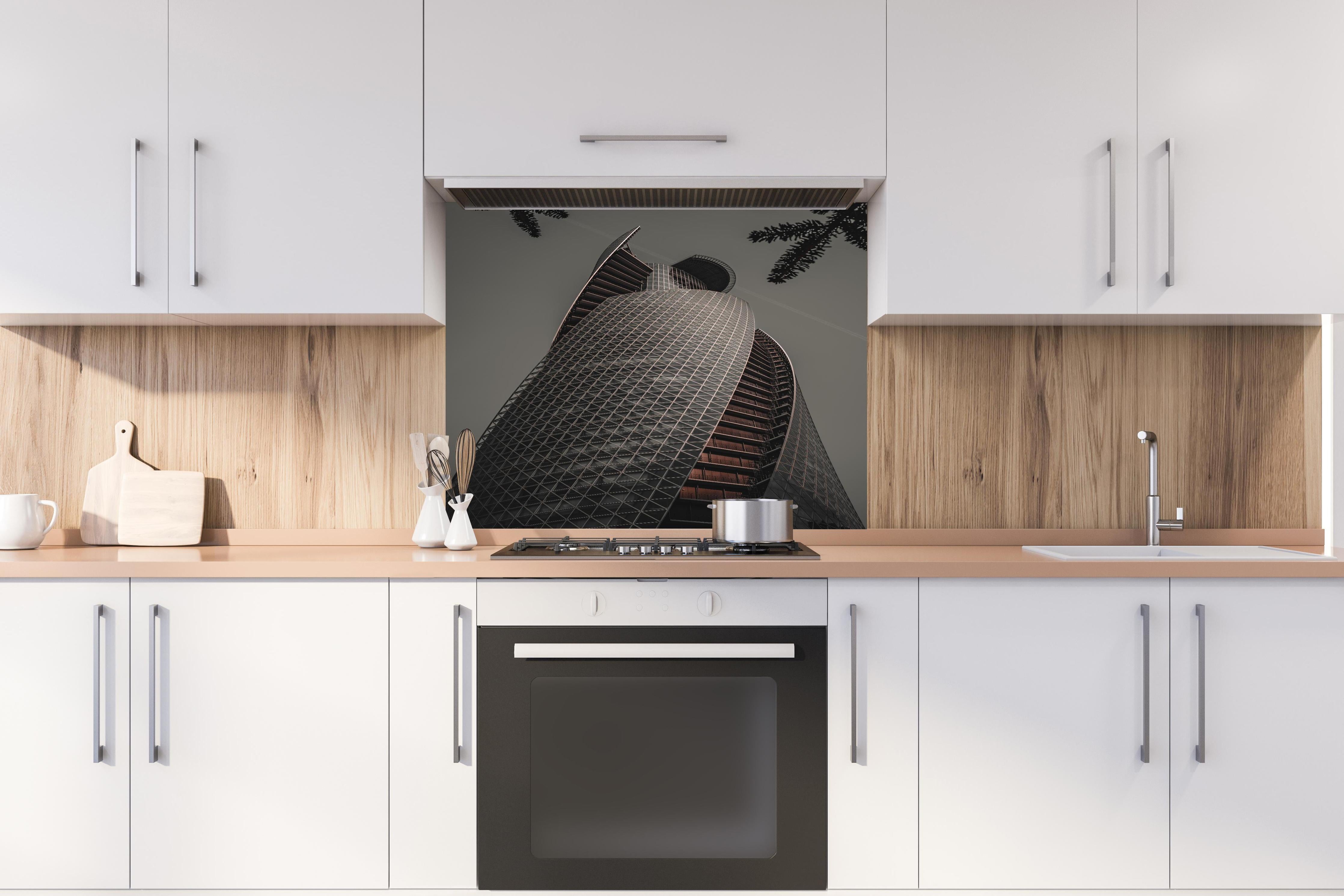 Spritzschutz - Modernes Spiral-Gebäude in Grautönen hinter einem Cerankochfeld zwischen Holz-Kochutensilien