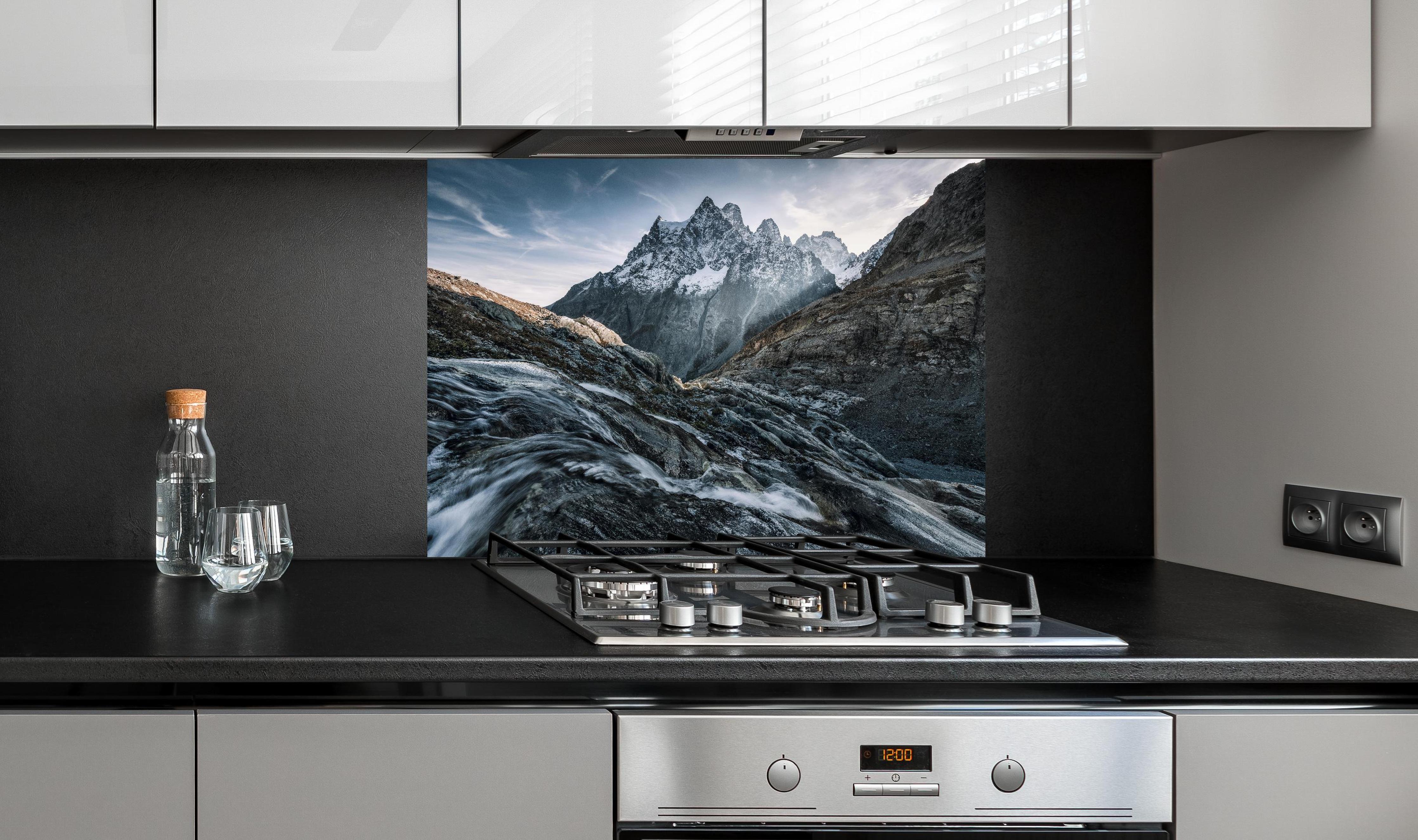 Spritzschutz - Monochrome Berggipfel mit Fluss hinter einem Cerankochfeld zwischen Holz-Kochutensilien