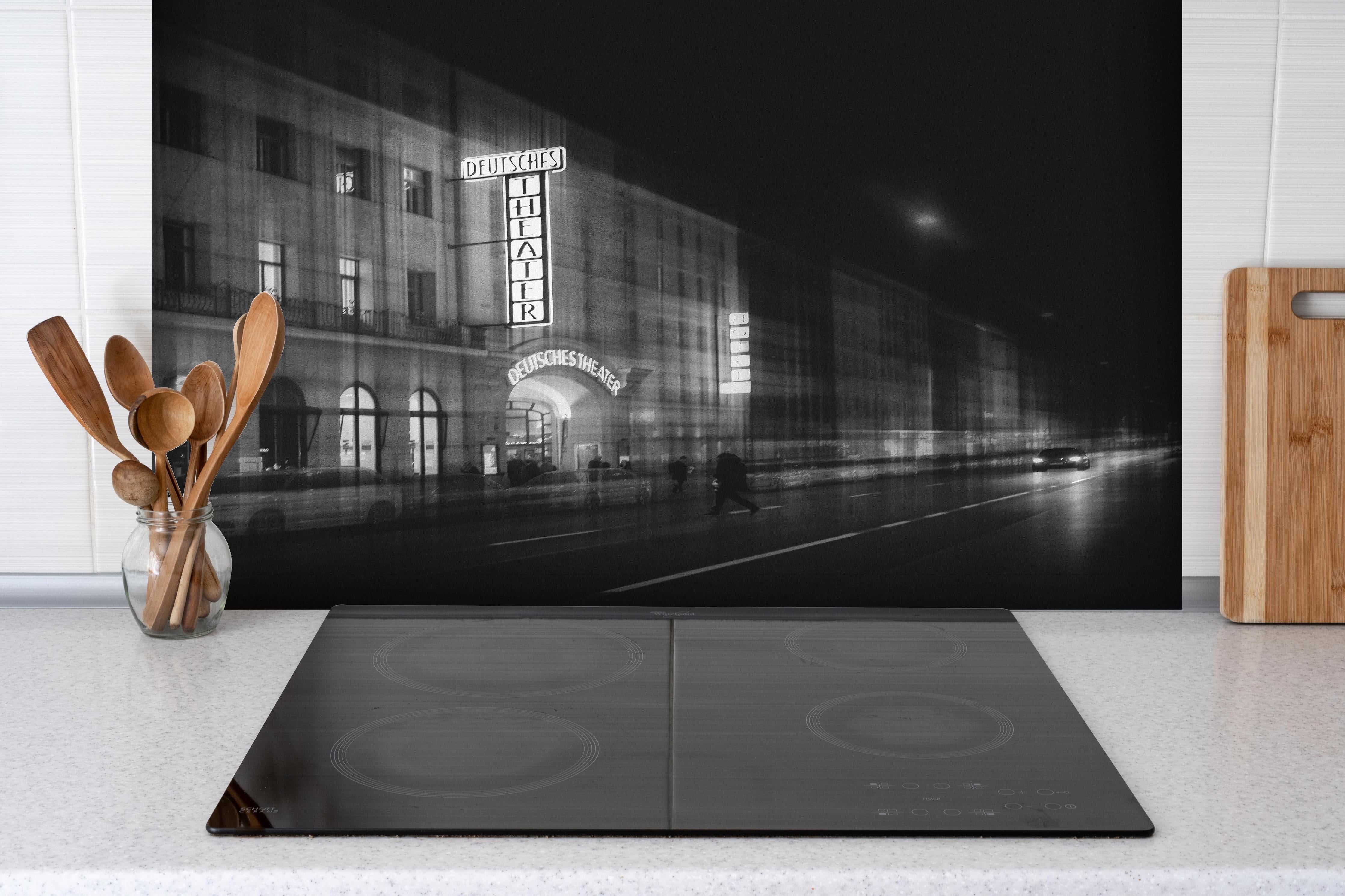 Spritzschutz - Monochrome Nachtansicht Deutsches Theater hinter einem Cerankochfeld zwischen Holz-Kochutensilien