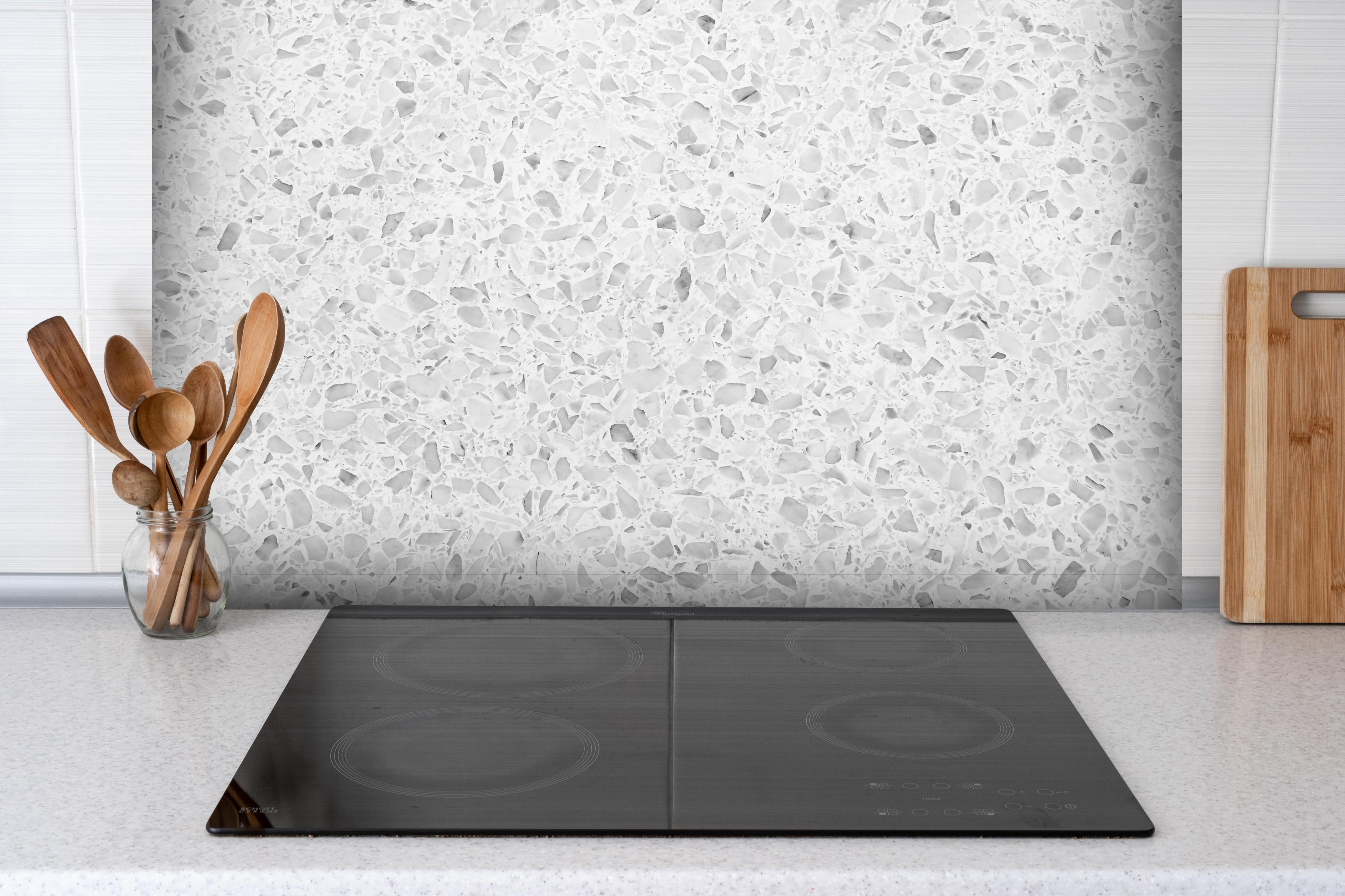 Spritzschutz - Monochrome Weiβ-Graue Terrazzo-Textur hinter einem Cerankochfeld zwischen Holz-Kochutensilien