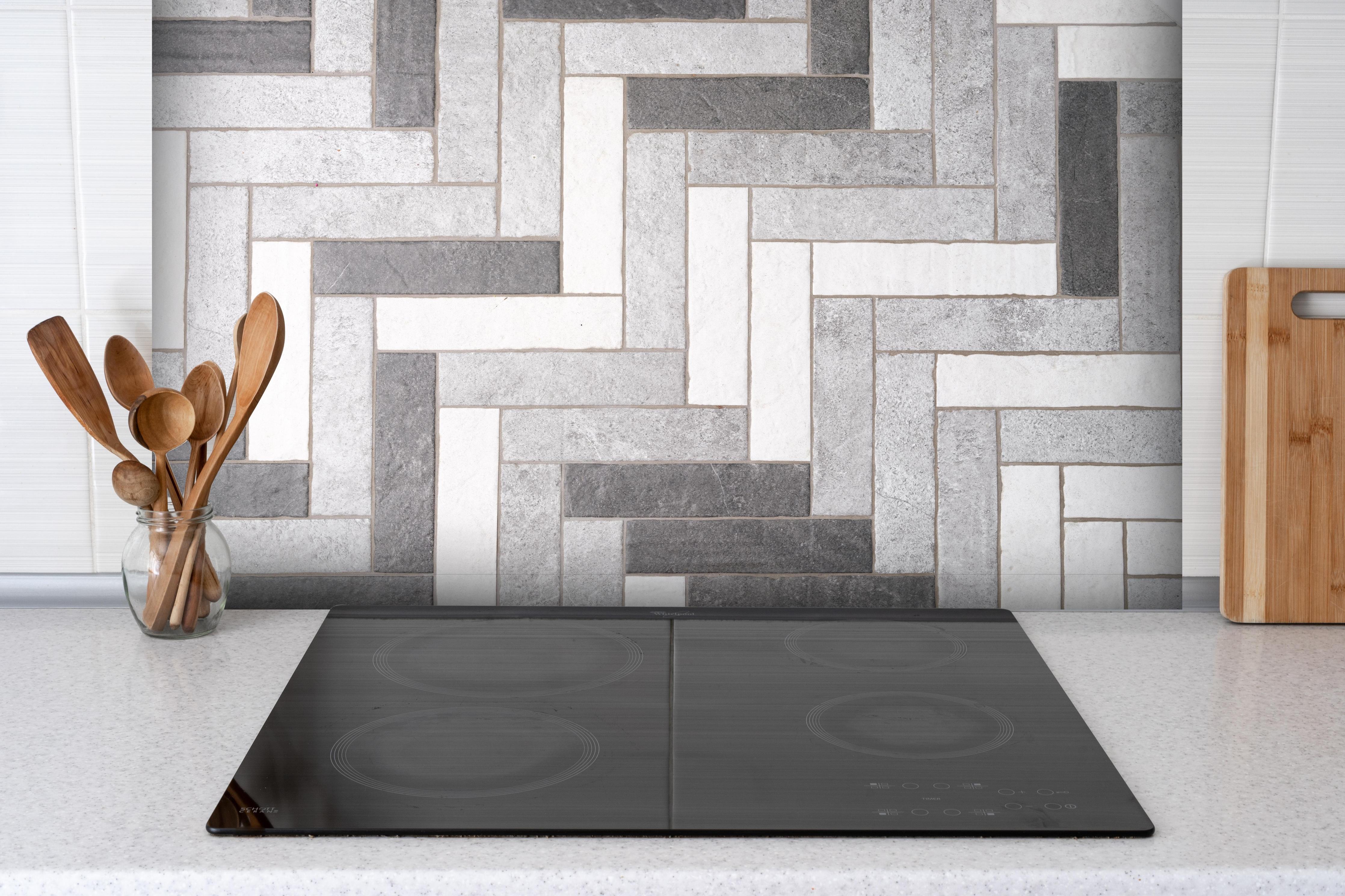 Spritzschutz - Mosaikbodenfliesen in Rechtecken hinter einem Cerankochfeld zwischen Holz-Kochutensilien