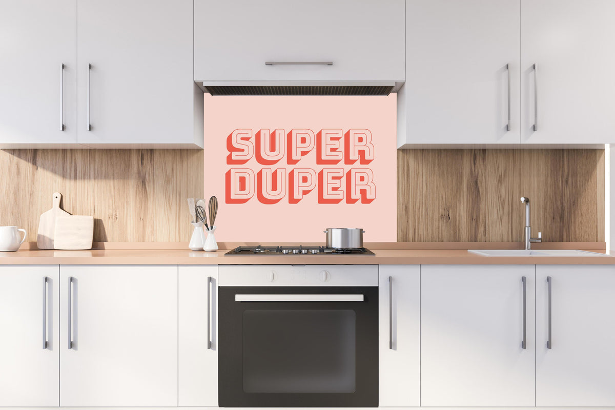 Spritzschutz - Motivationaler 'Super Duper' Schriftzug in Pink hinter einem Cerankochfeld zwischen Holz-Kochutensilien