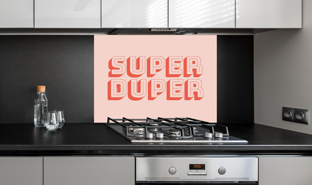 Spritzschutz - Motivationaler 'Super Duper' Schriftzug in Pink hinter einem Cerankochfeld zwischen Holz-Kochutensilien