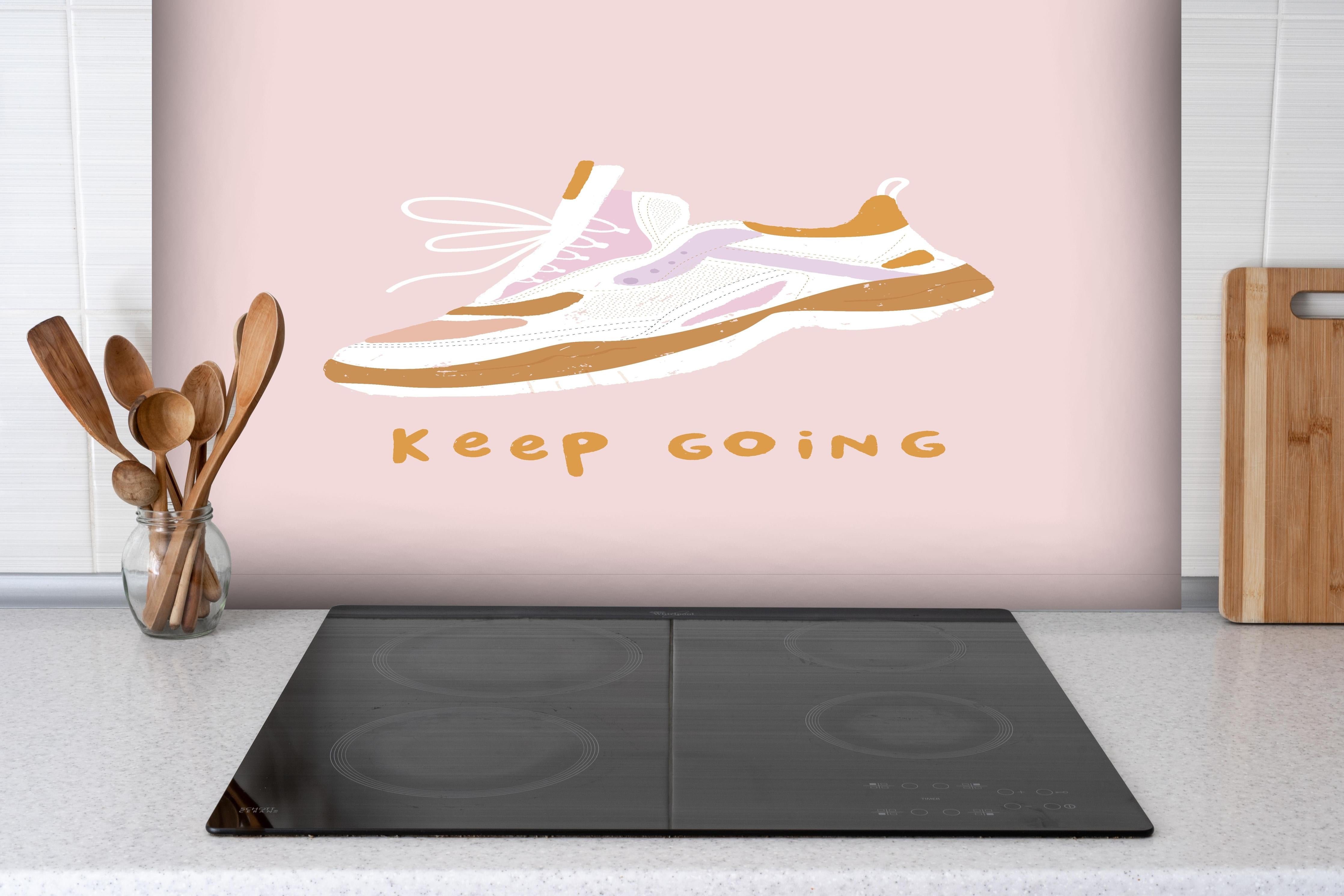 Spritzschutz - Motivierender Walking-Schuh auf Rosa hinter einem Cerankochfeld zwischen Holz-Kochutensilien