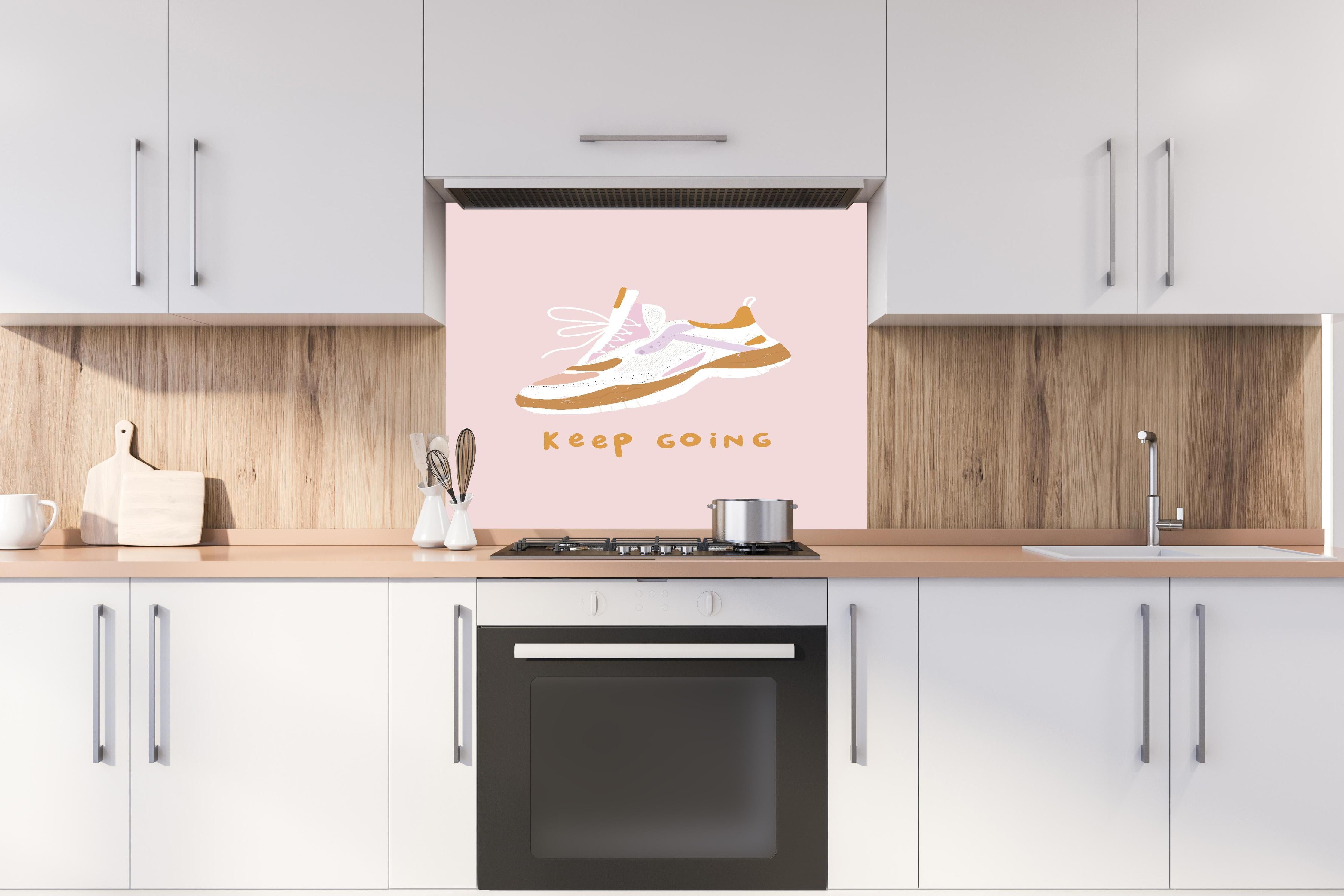 Spritzschutz - Motivierender Walking-Schuh auf Rosa hinter einem Cerankochfeld zwischen Holz-Kochutensilien