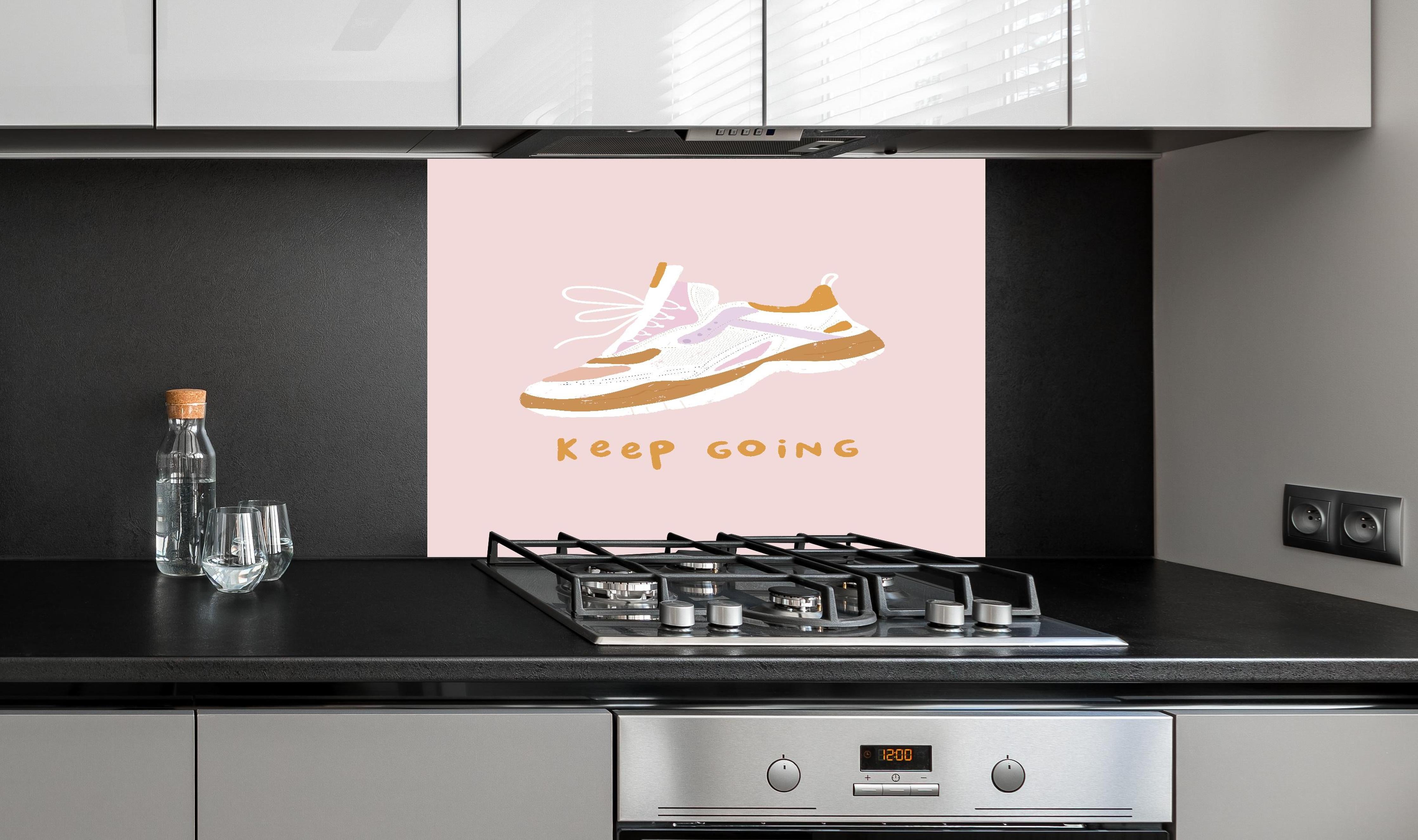 Spritzschutz - Motivierender Walking-Schuh auf Rosa hinter einem Cerankochfeld zwischen Holz-Kochutensilien