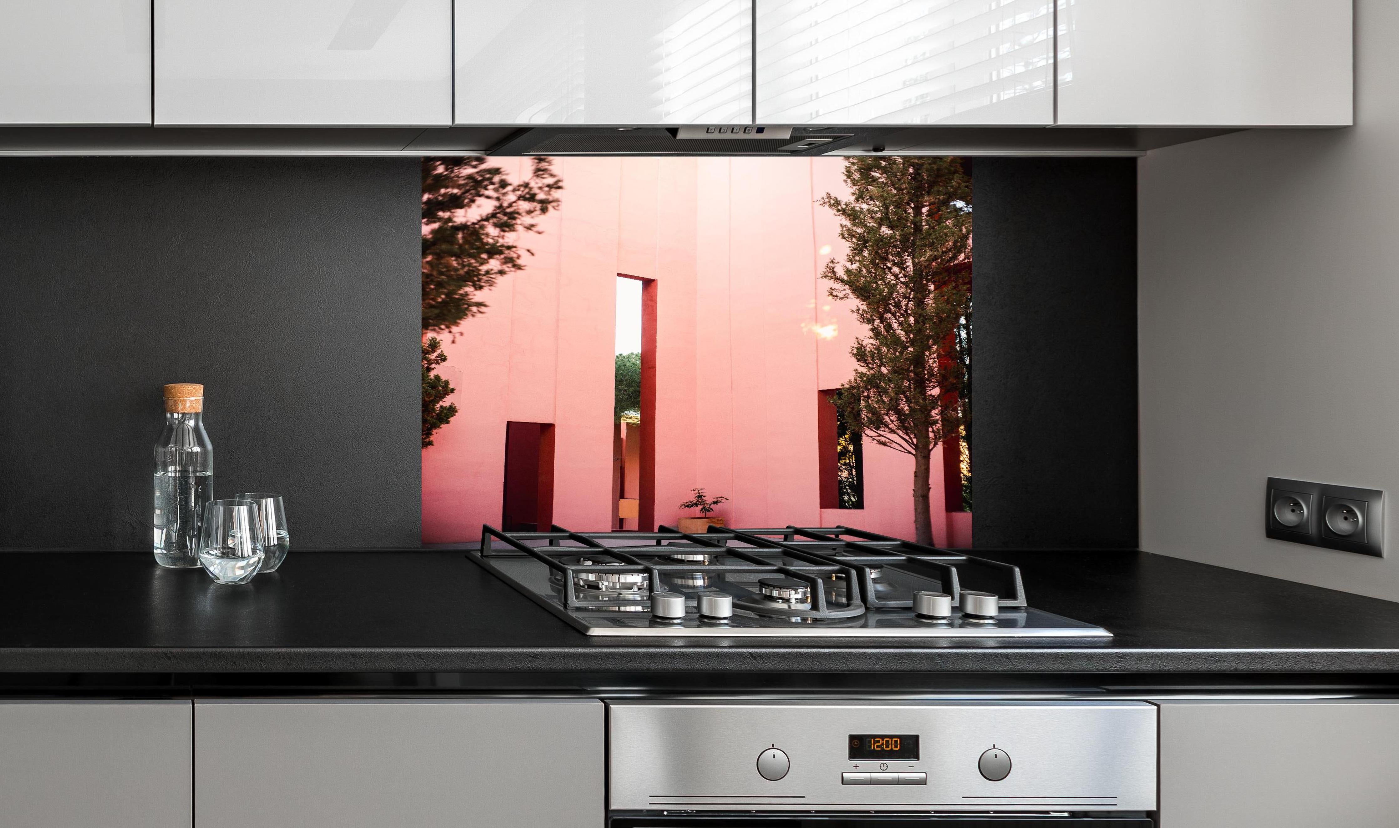 Spritzschutz - Muralla Roja Eingang in zartem Pink hinter einem Cerankochfeld zwischen Holz-Kochutensilien