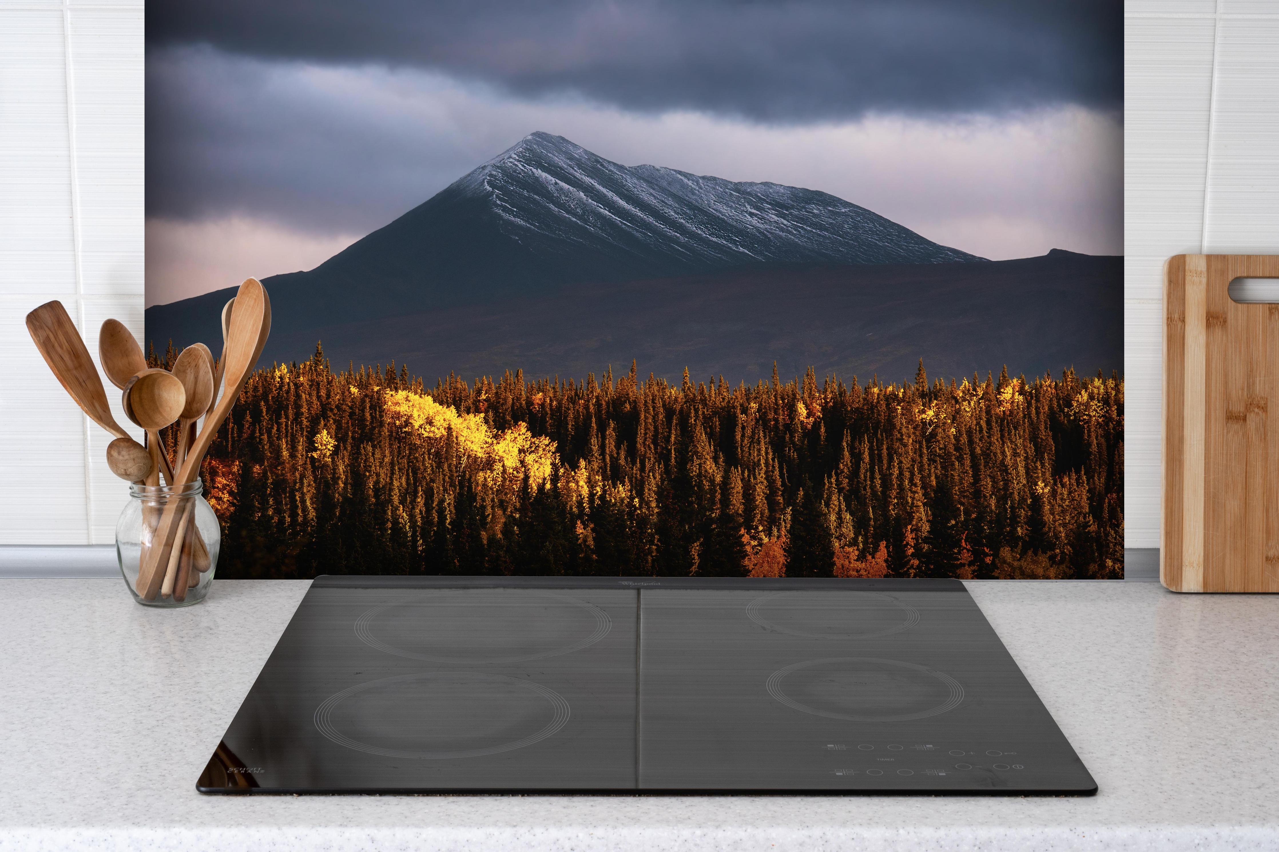 Spritzschutz - Mystische Berge im herbstlichen Morgenlicht hinter einem Cerankochfeld zwischen Holz-Kochutensilien